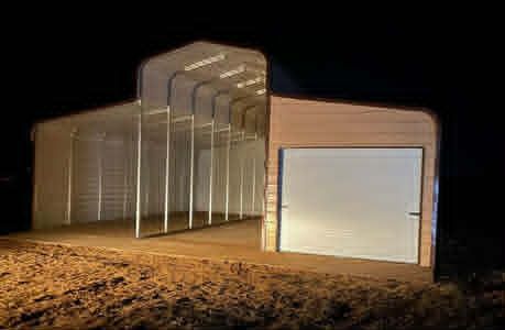 Outdoor photo of a modern building with a large white garage door and transparent side panels at dusk