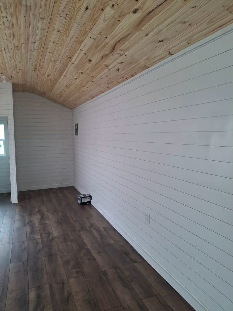 Interior room with dark wood-look flooring, light-colored slat walls, and a sloped, natural-finish wood ceiling.
