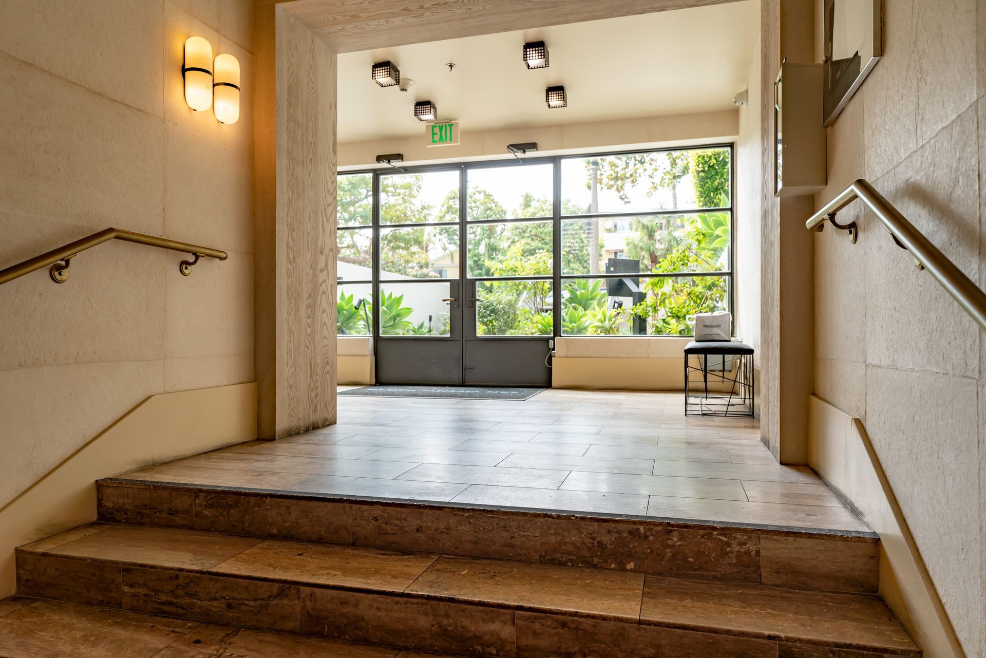 Stone stairs leading to a doorway, with a view of greenery beyond.