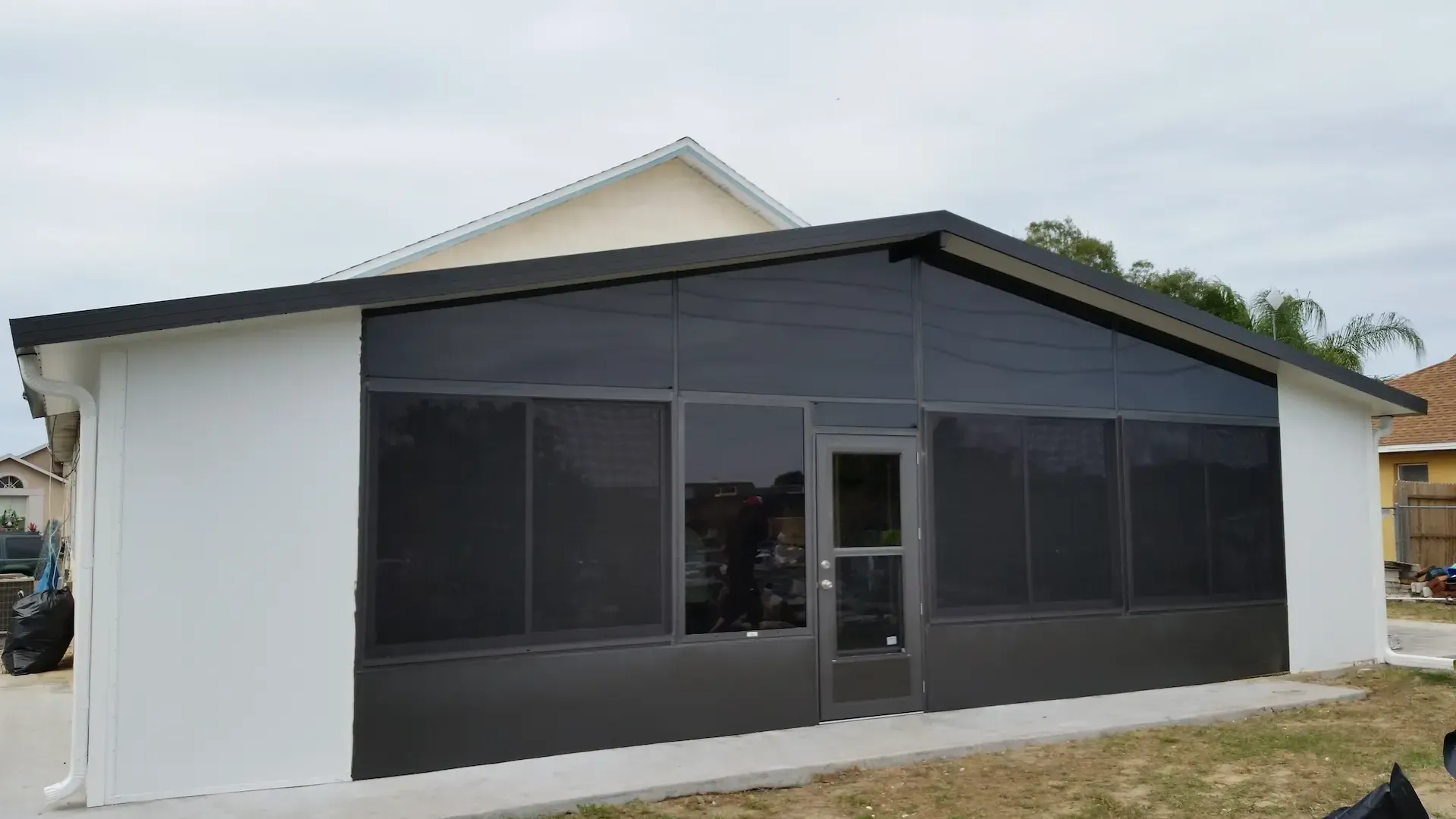 A white house with a screened in porch and a black door.