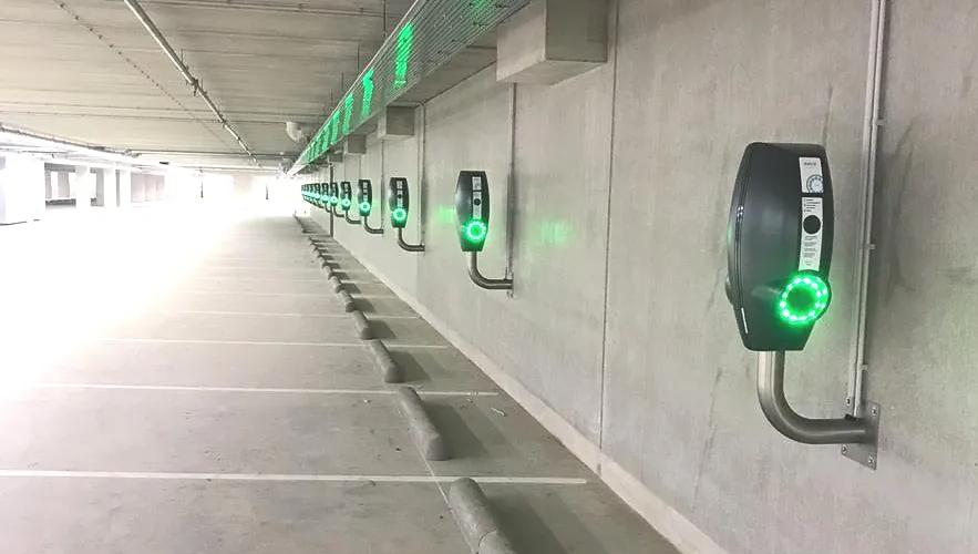 Een rij groene laadstations/laadpalen in een parkeergarage.