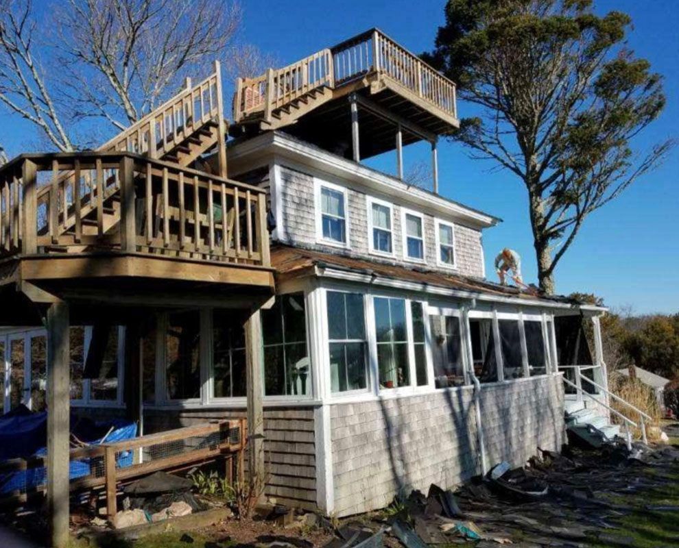 Wooden house with multiple decks, including a rooftop deck; sunny day.