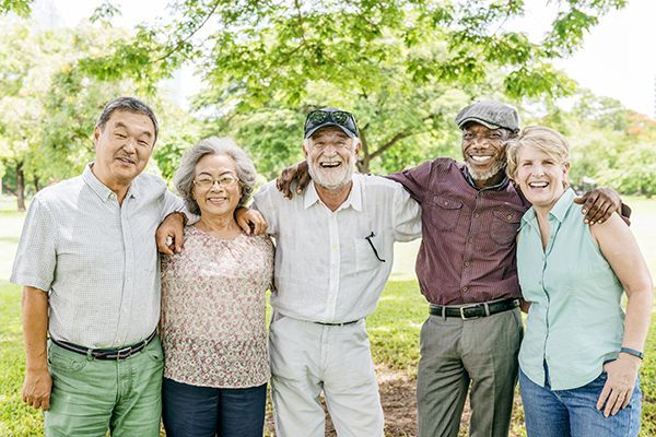 Friends with arms over shoulders in a park. Senior age.