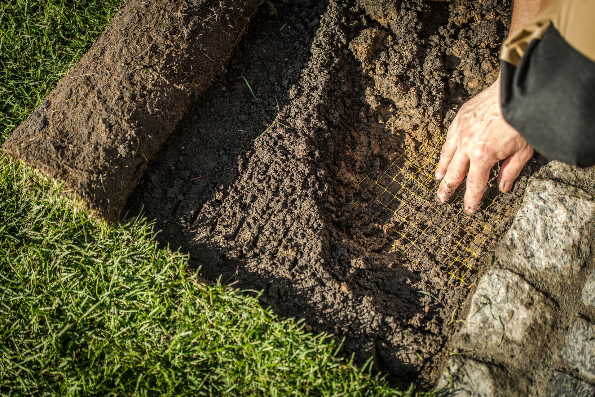 Person rolling out sod on grass.