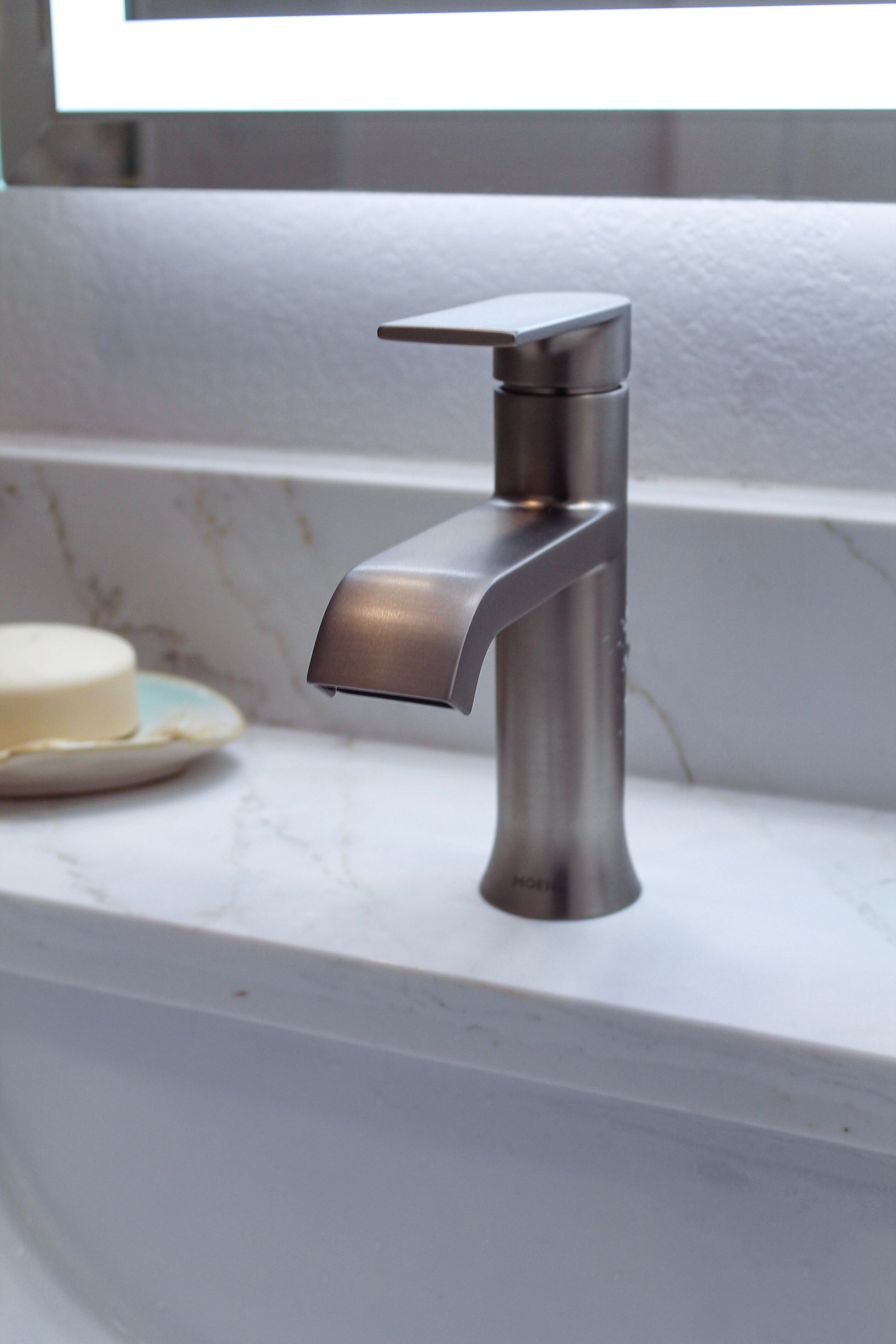 modern stainless steel tap on white quartz countertop, white sink and modern artistic soap holder, with LED LIT mirror 