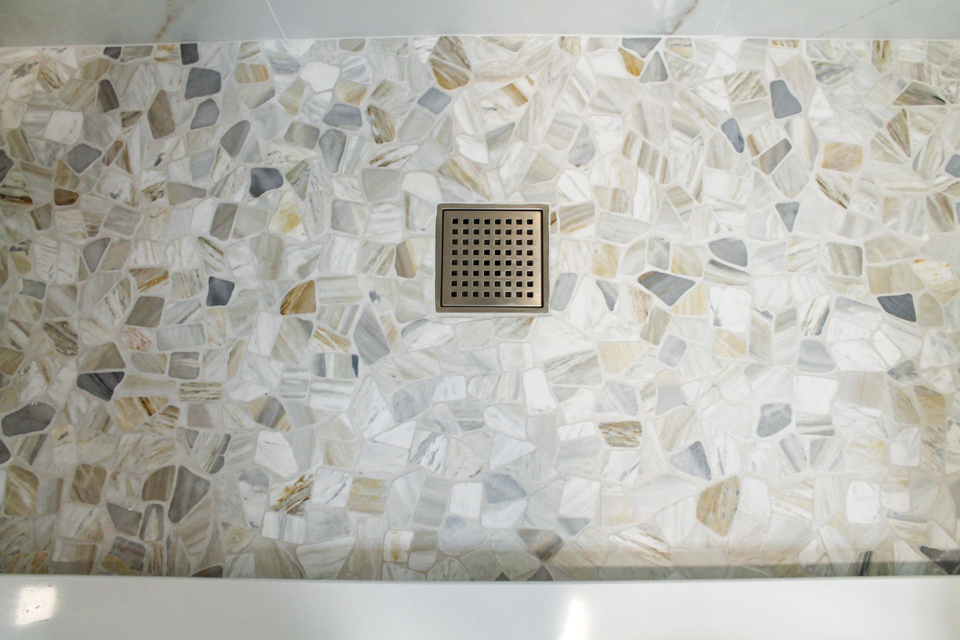 White pebble mosaic flooring modern brushed stainless steel drain and white grout