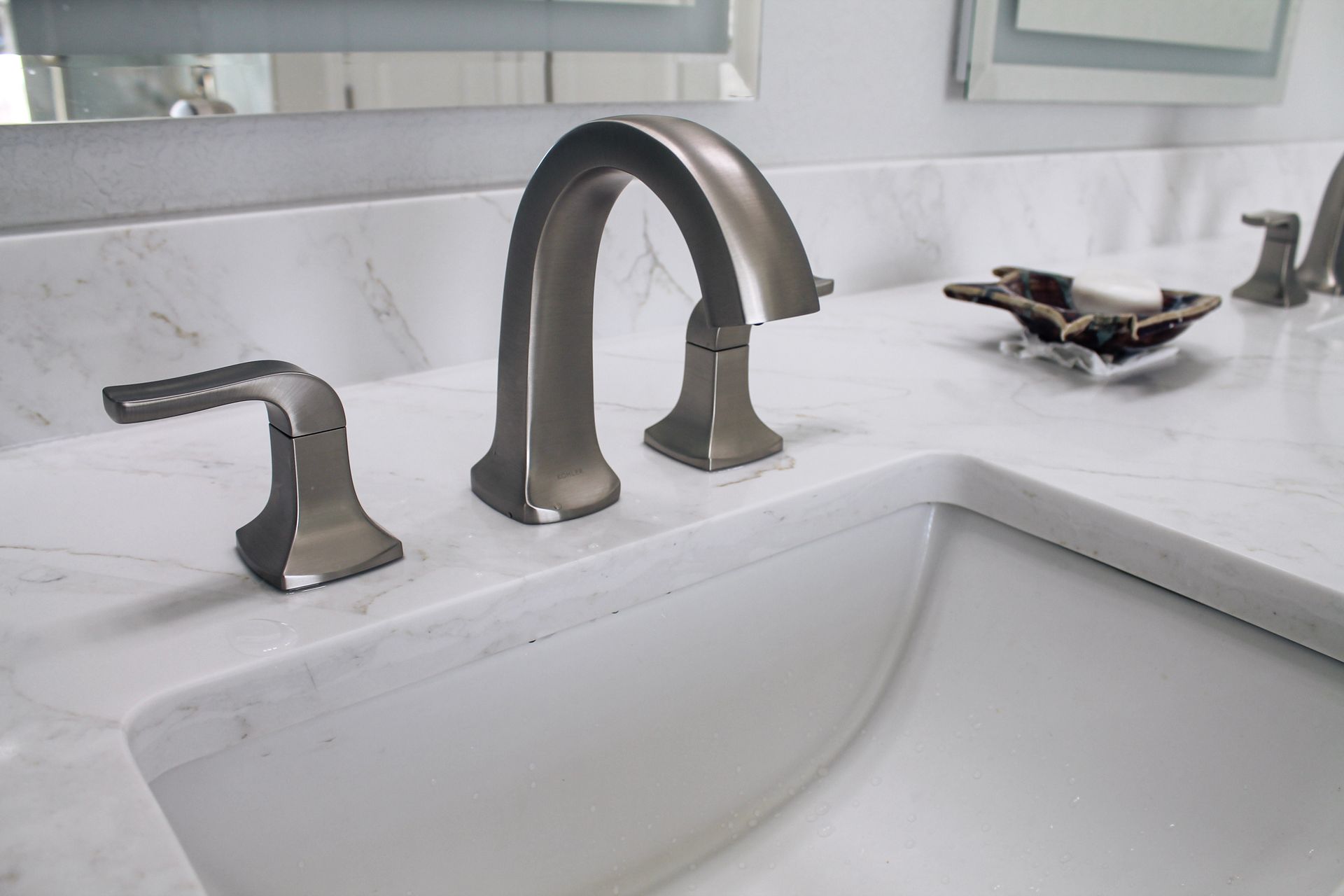 White quartz countertop with modern brushed stainless steel tap and handles with white sink, Grey walls and modern artistic soap holder