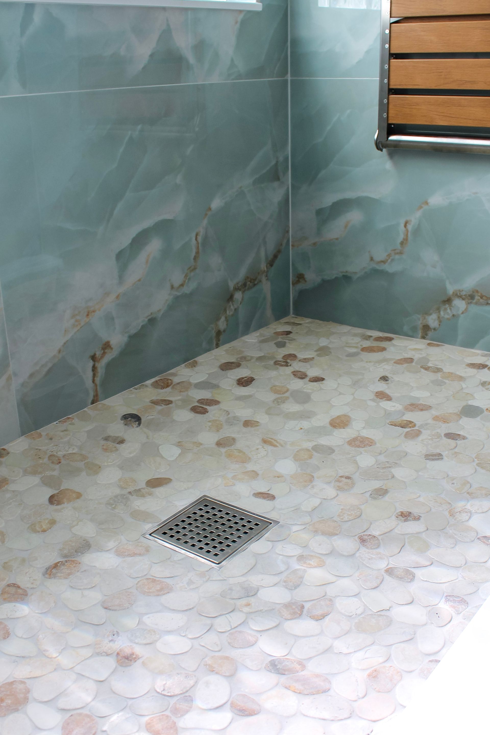 Modern blue tile bathroom with glass block window, white grout, steel and wood bench, Niche with white trims and mosaic, modern mosaic flooring with white grout close up