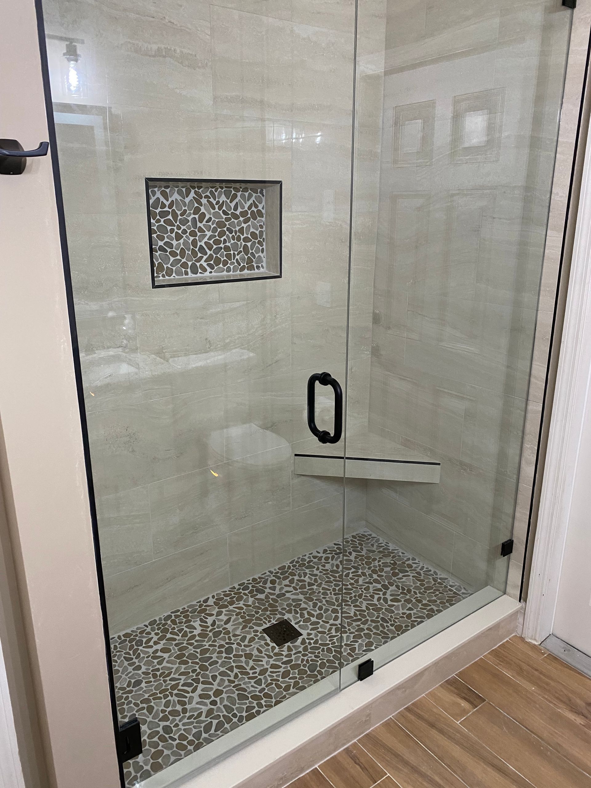 A bathroom with a walk in shower with a glass door.