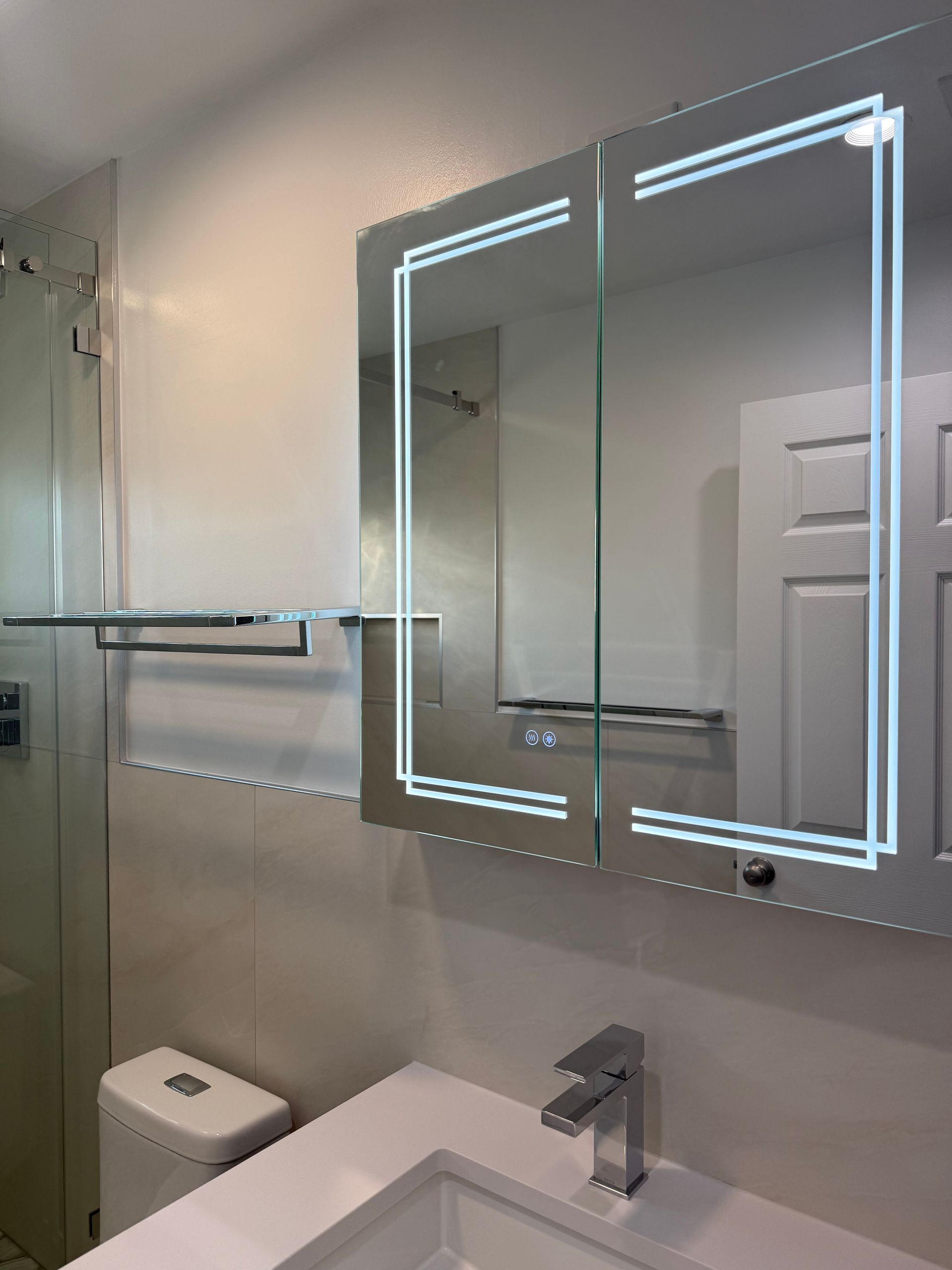 Remodeled bathroom vanity area with white quartz countertop, modern faucet, and mirrored medicine cabinet above beige wall tile