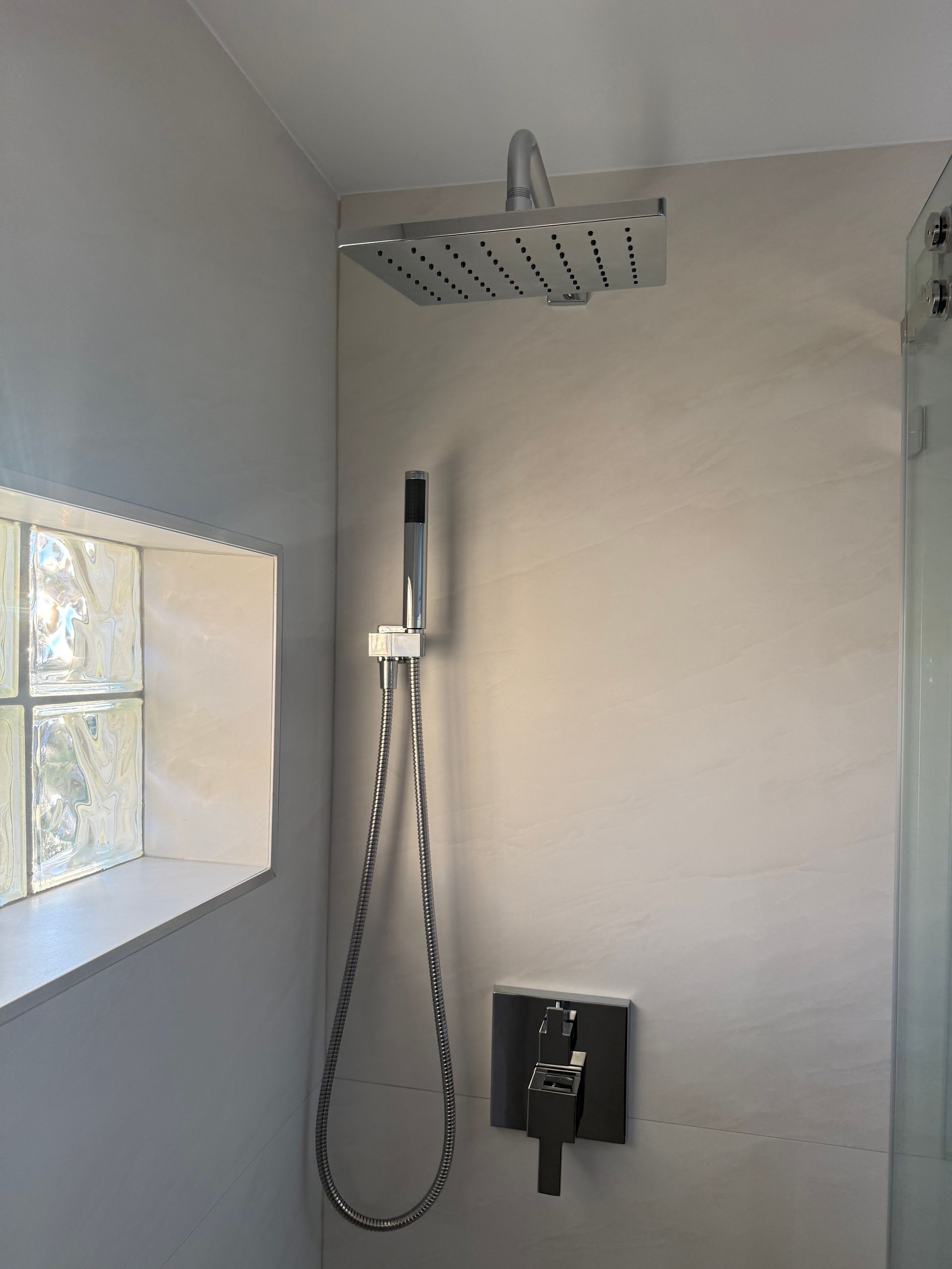 Updated bathroom shower with rainfall shower head and beige wall tile,