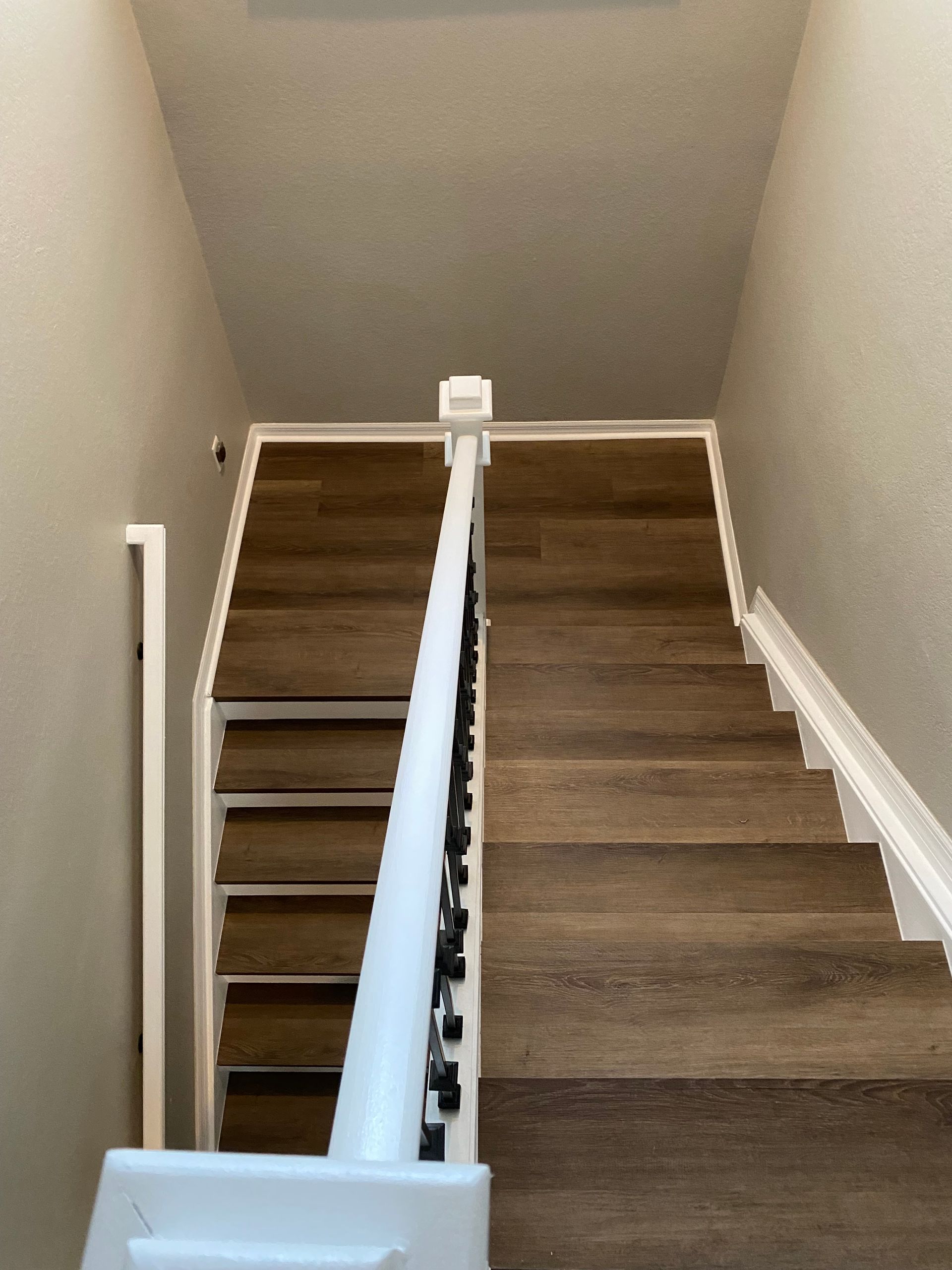 Brown oak luxury vinyl plank staircase with white railing and black accents installed by Fort Myers remodeling contractor Style Home Remodeling.