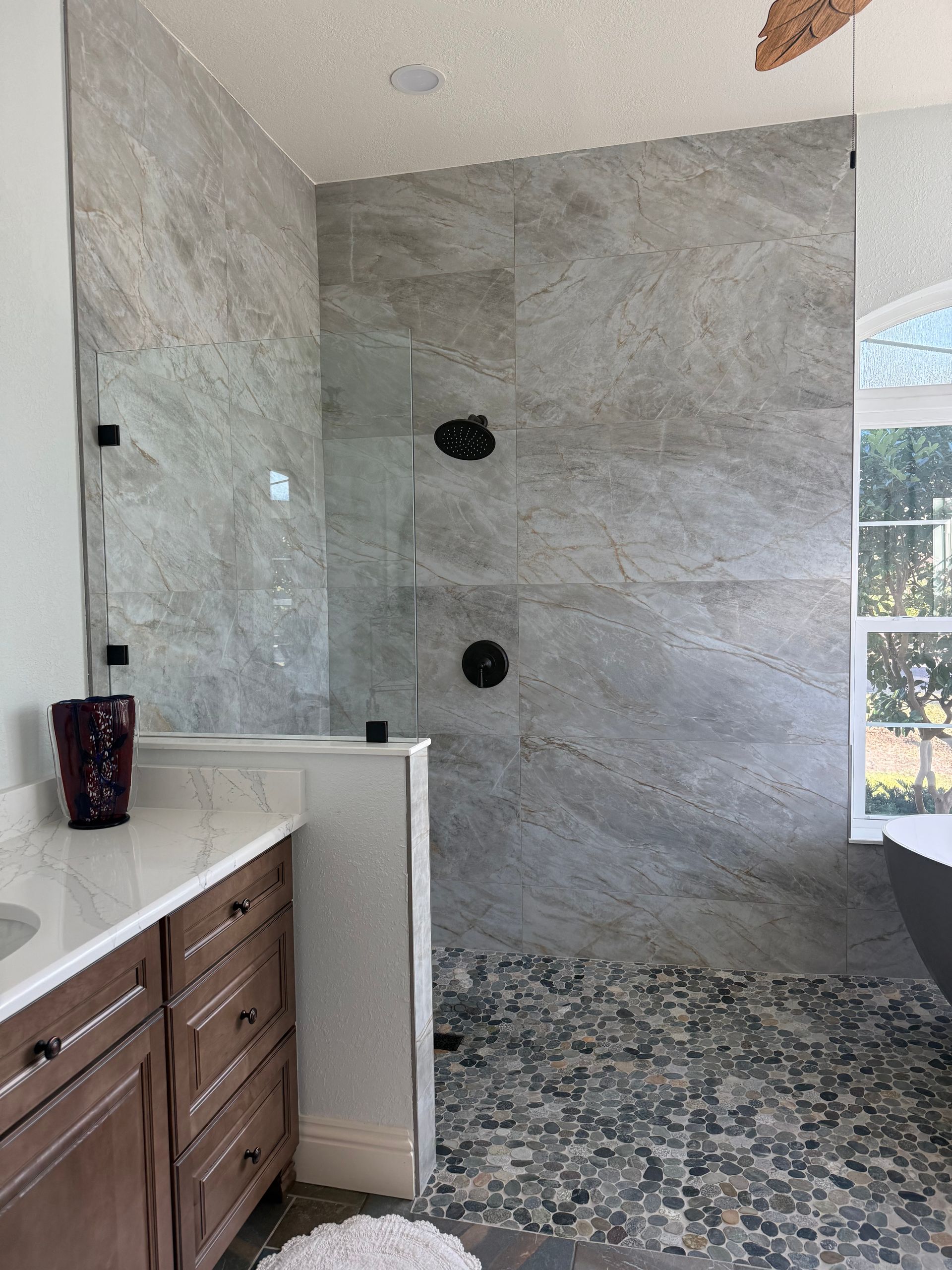 Fort Myers bathroom renovation by Style Home Remodeling, showcasing a brown oak vanity, white quartz