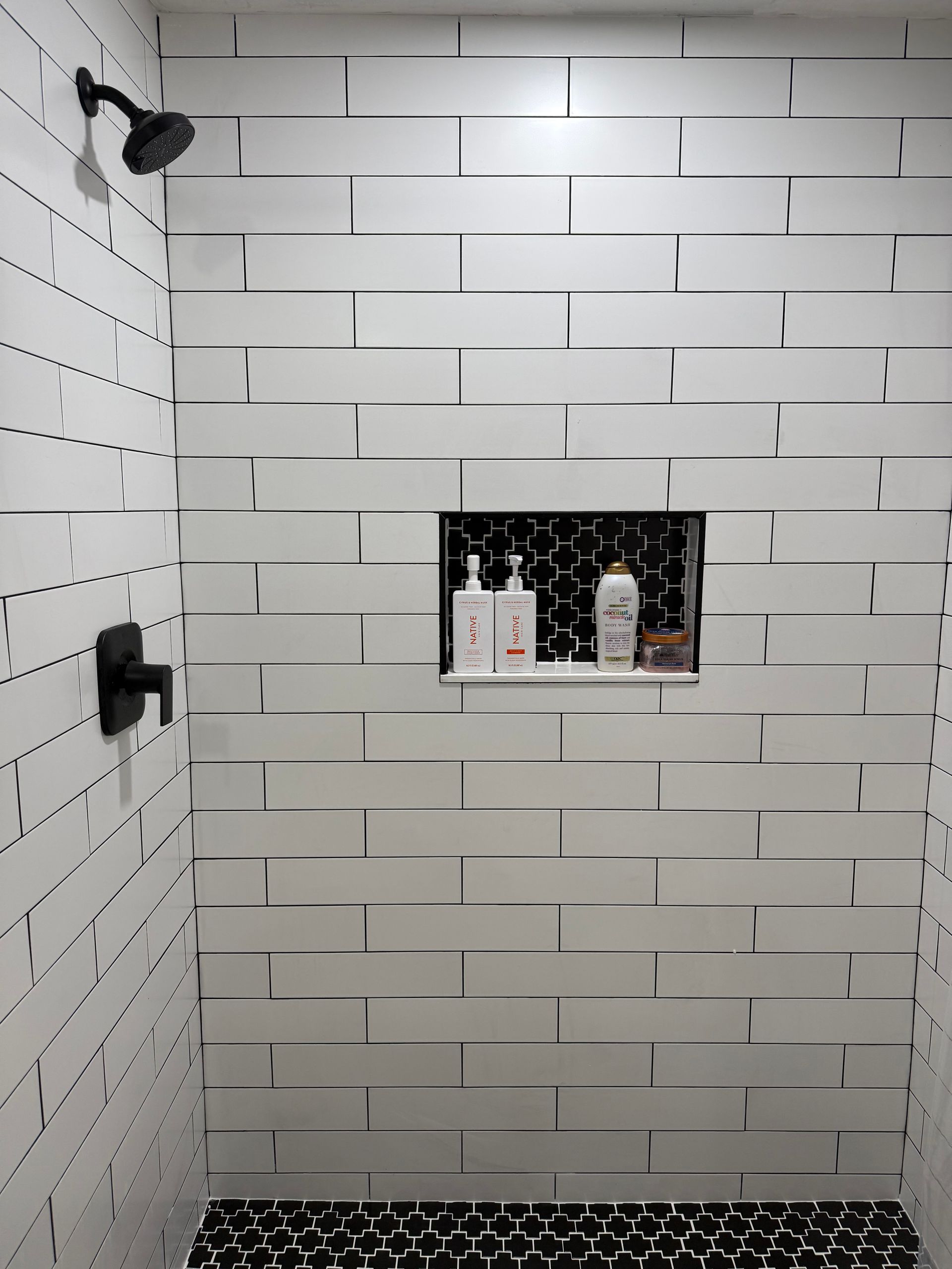 a shower with white and black tile
