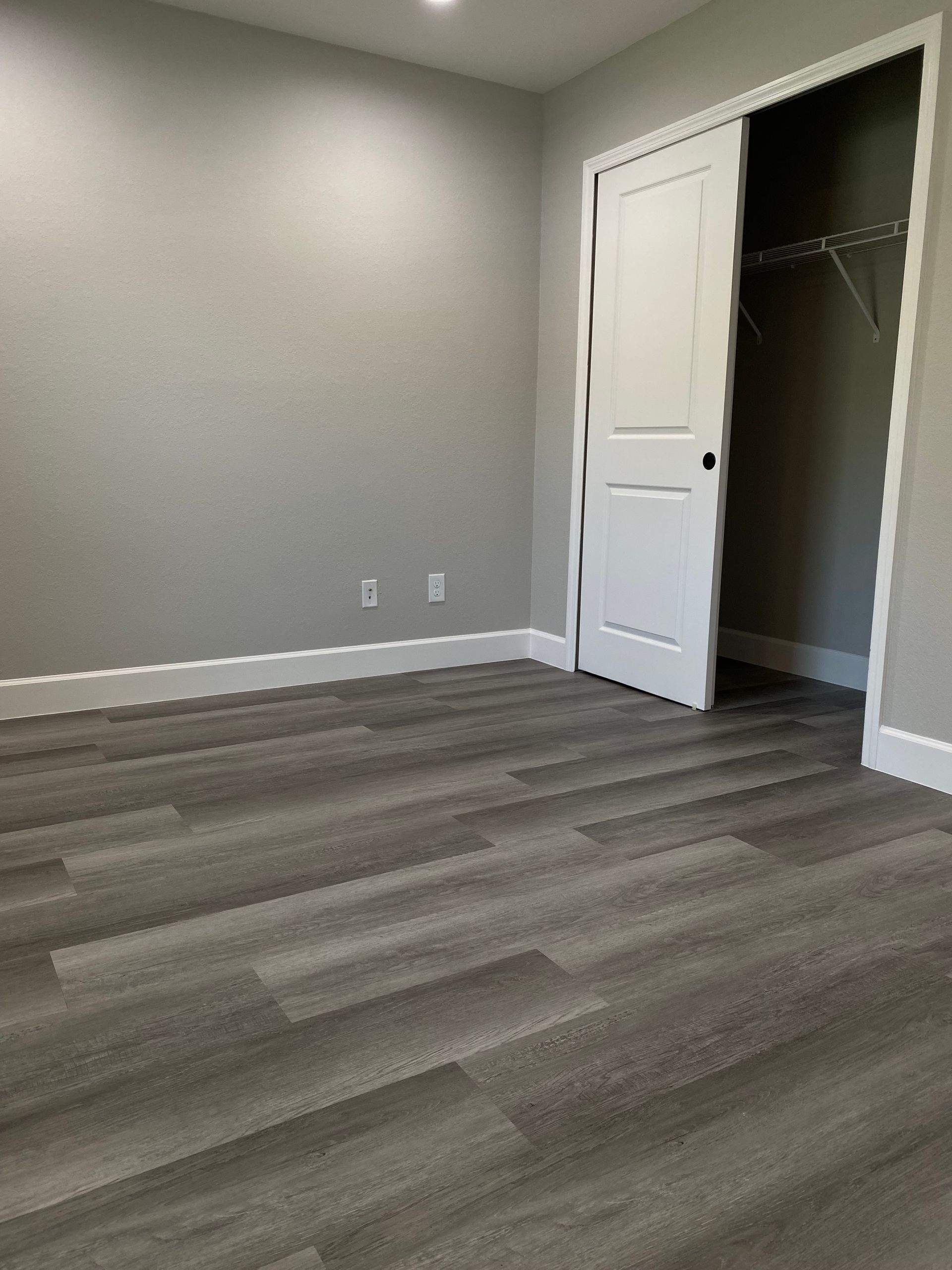 An empty room with gray floors and a bi-fold door
