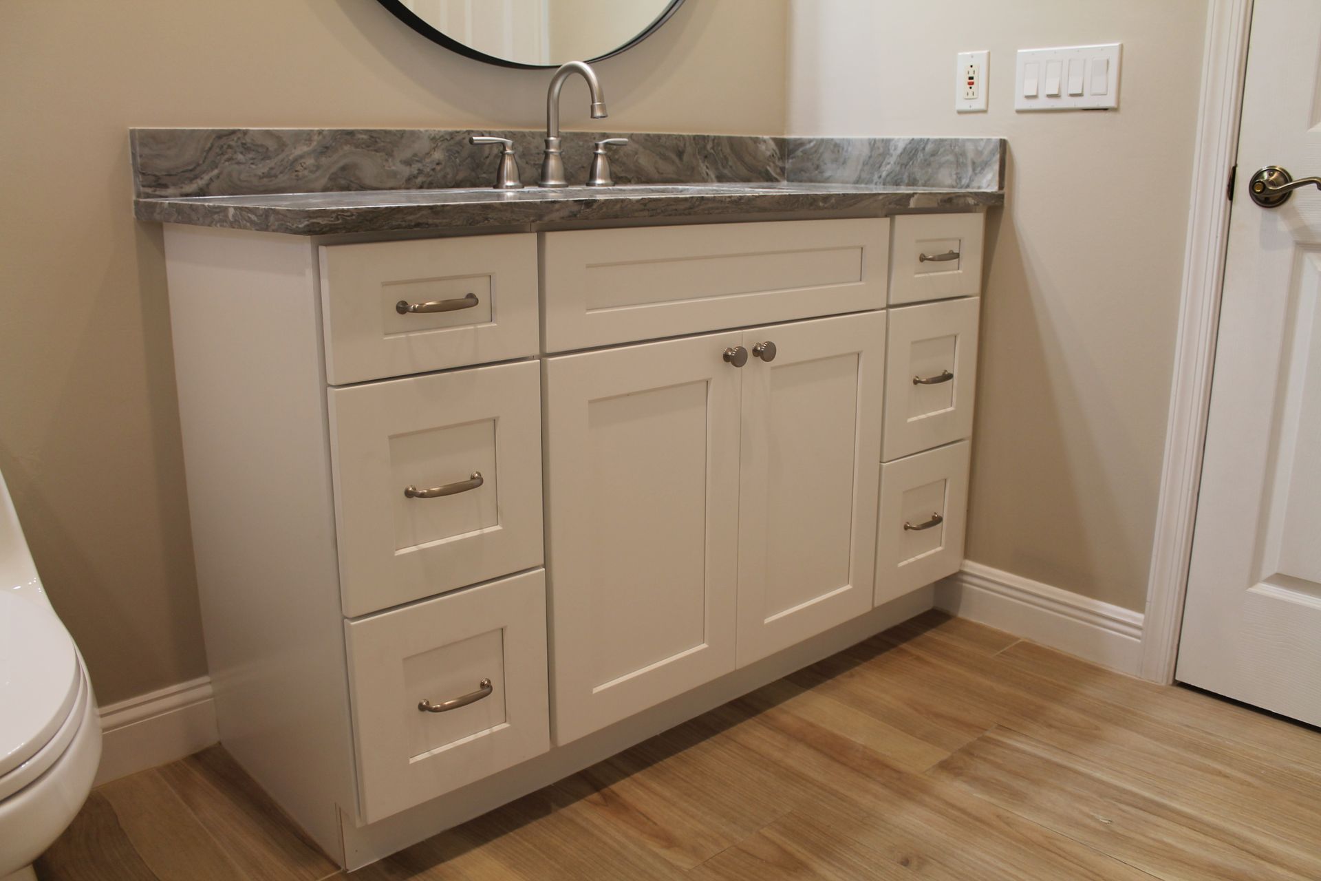 A bathroom with a sink and a round mirror.