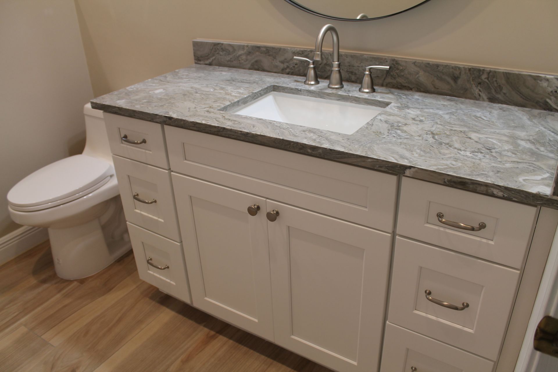 A bathroom with a sink and a round mirror.