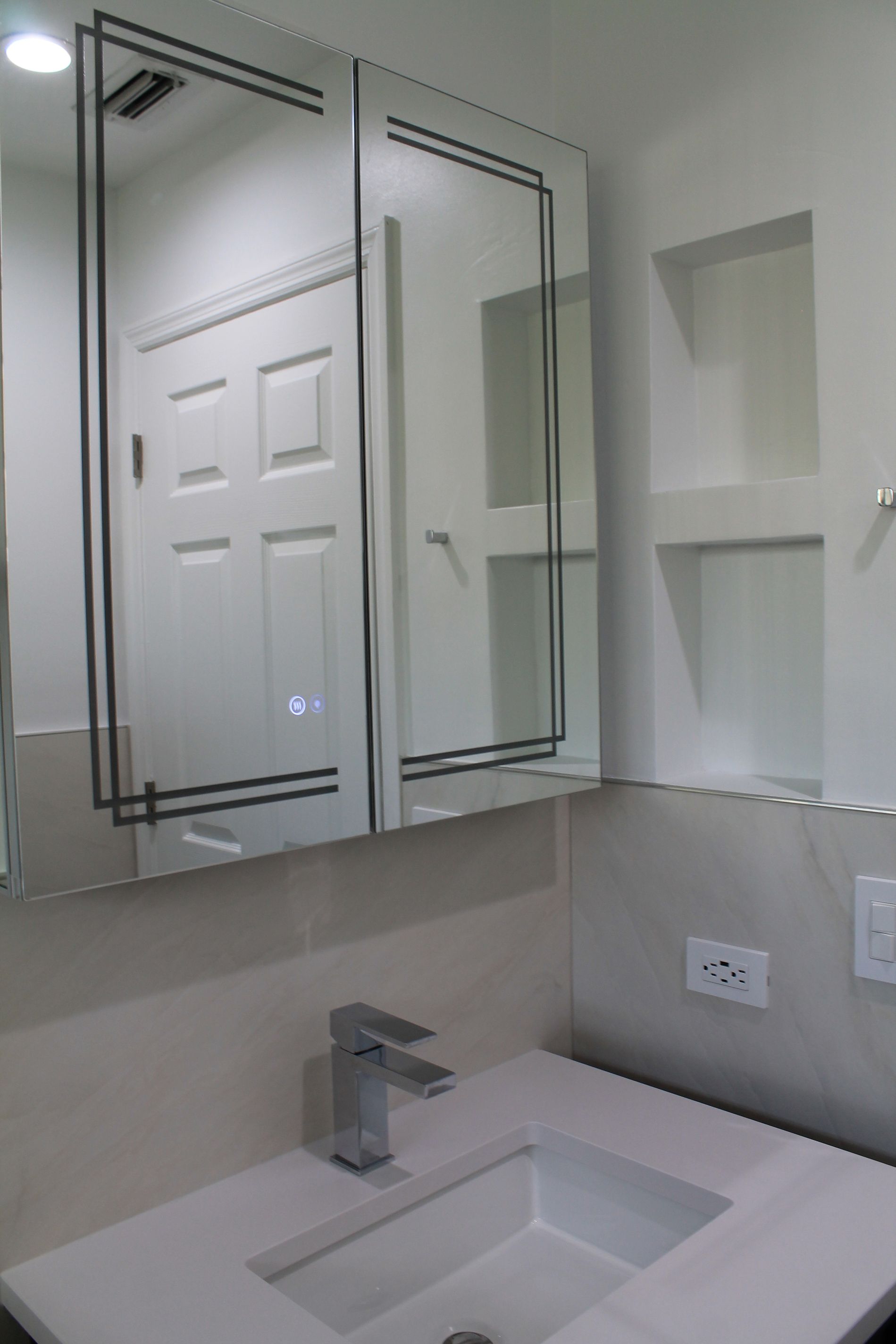 Remodeled bathroom vanity area with dark walnut cabinet, white quartz countertop, modern faucet, and mirrored medicine cabinet above beige wall tile