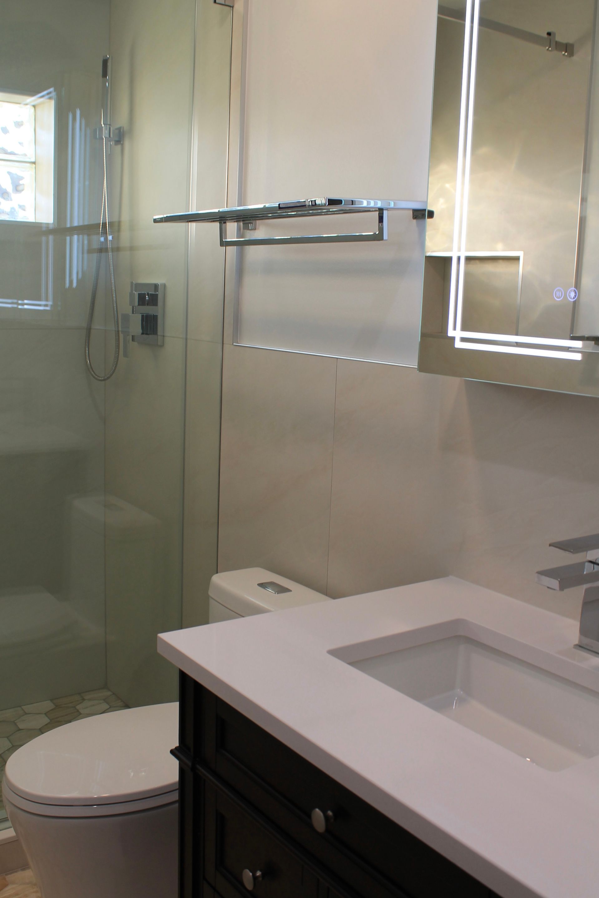 Bathroom remodel featuring a white toilet and dark walnut vanity with quartz countertop.