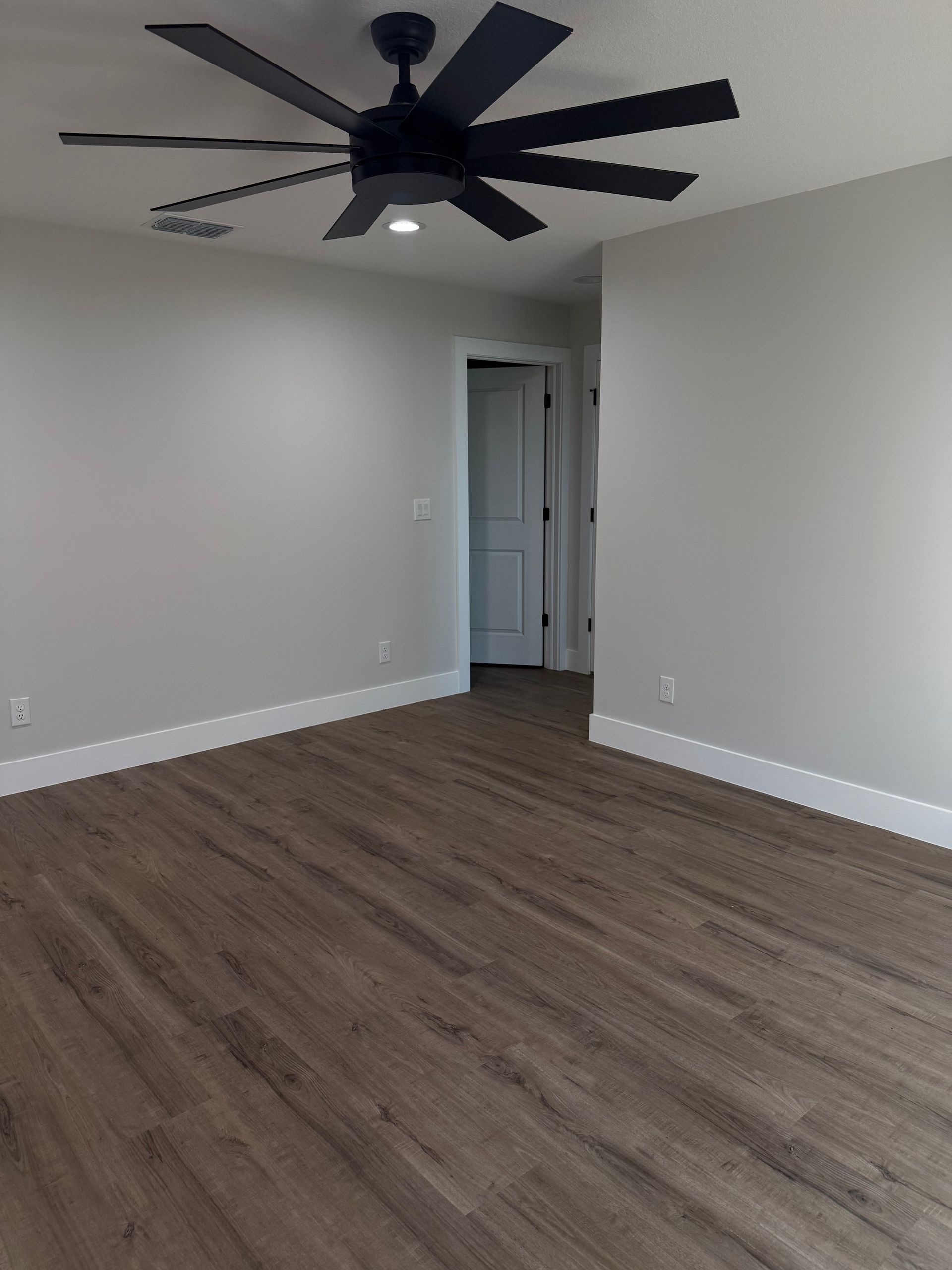 Brown SPC 5.5mm 12mil 20 mil Vinyl Flooring with attached IXPE padding Stone core flooring, brown oak wood look Vinyl click lock flooring with black fan, white modern square baseboard, modern flooring and black fan 