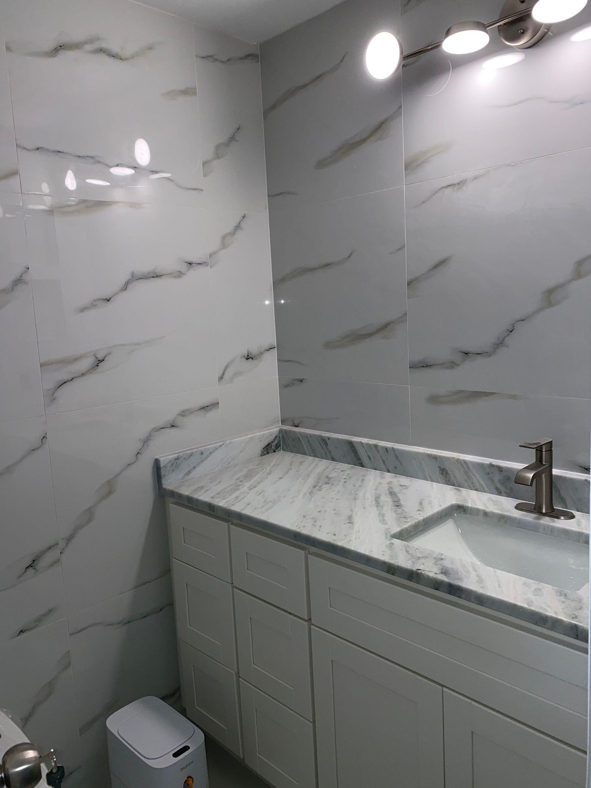 A bathroom with marble counter tops , a sink , and a toilet.