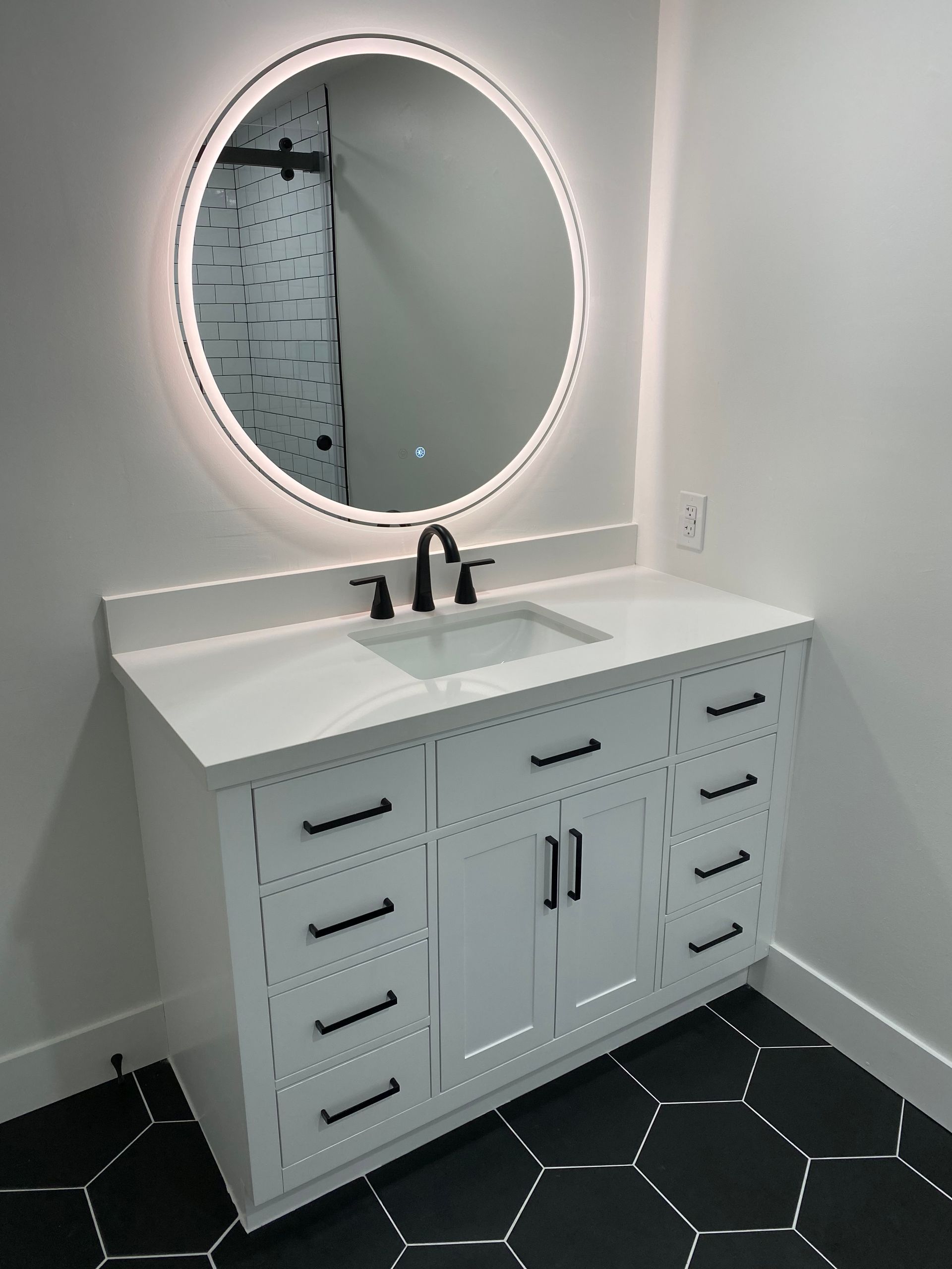 A bathroom with a sink and a round mirror.