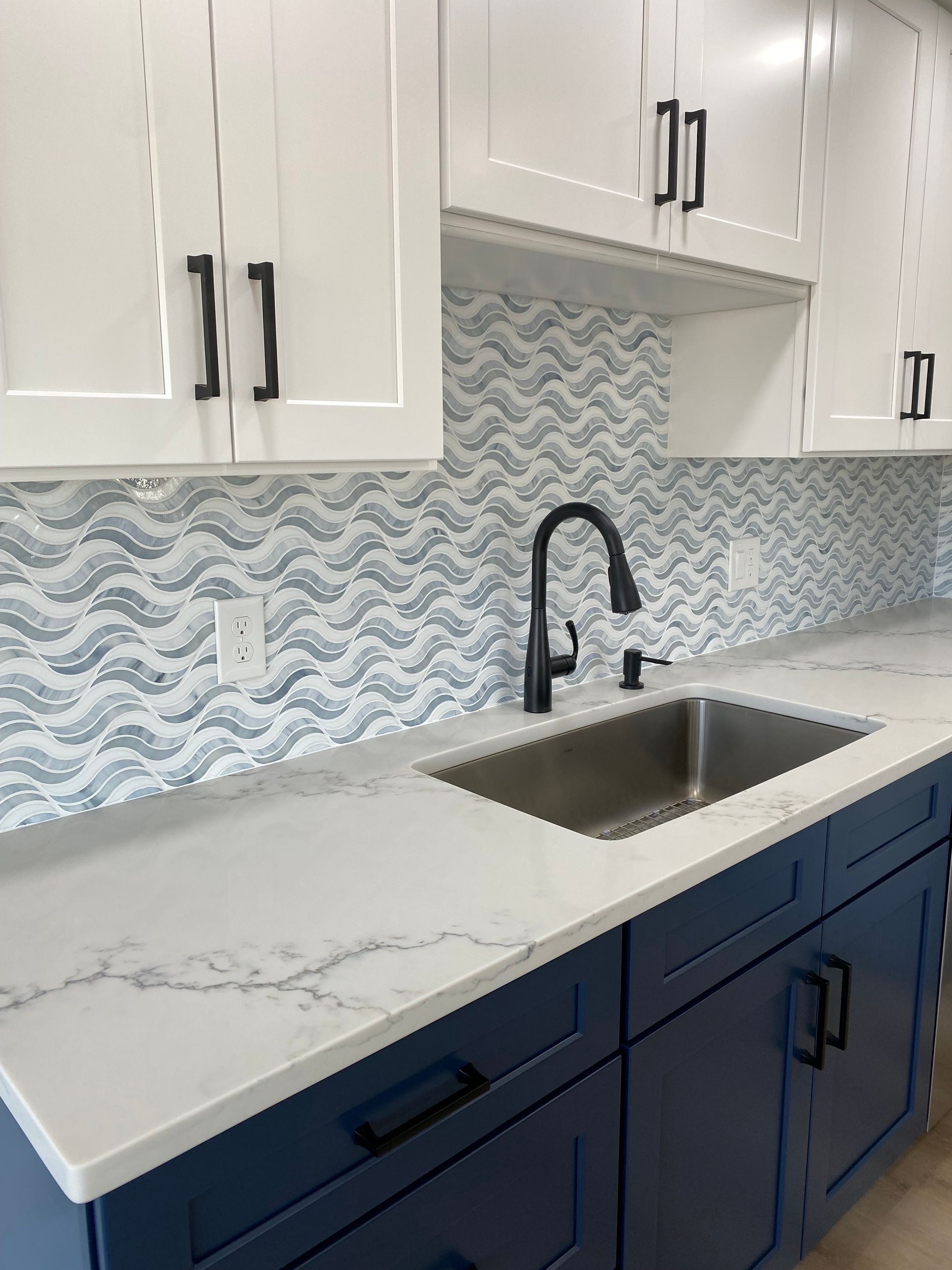 
Modern blue shaker cabinets with white quartz countertops and a matching patterned tile backsplash 
