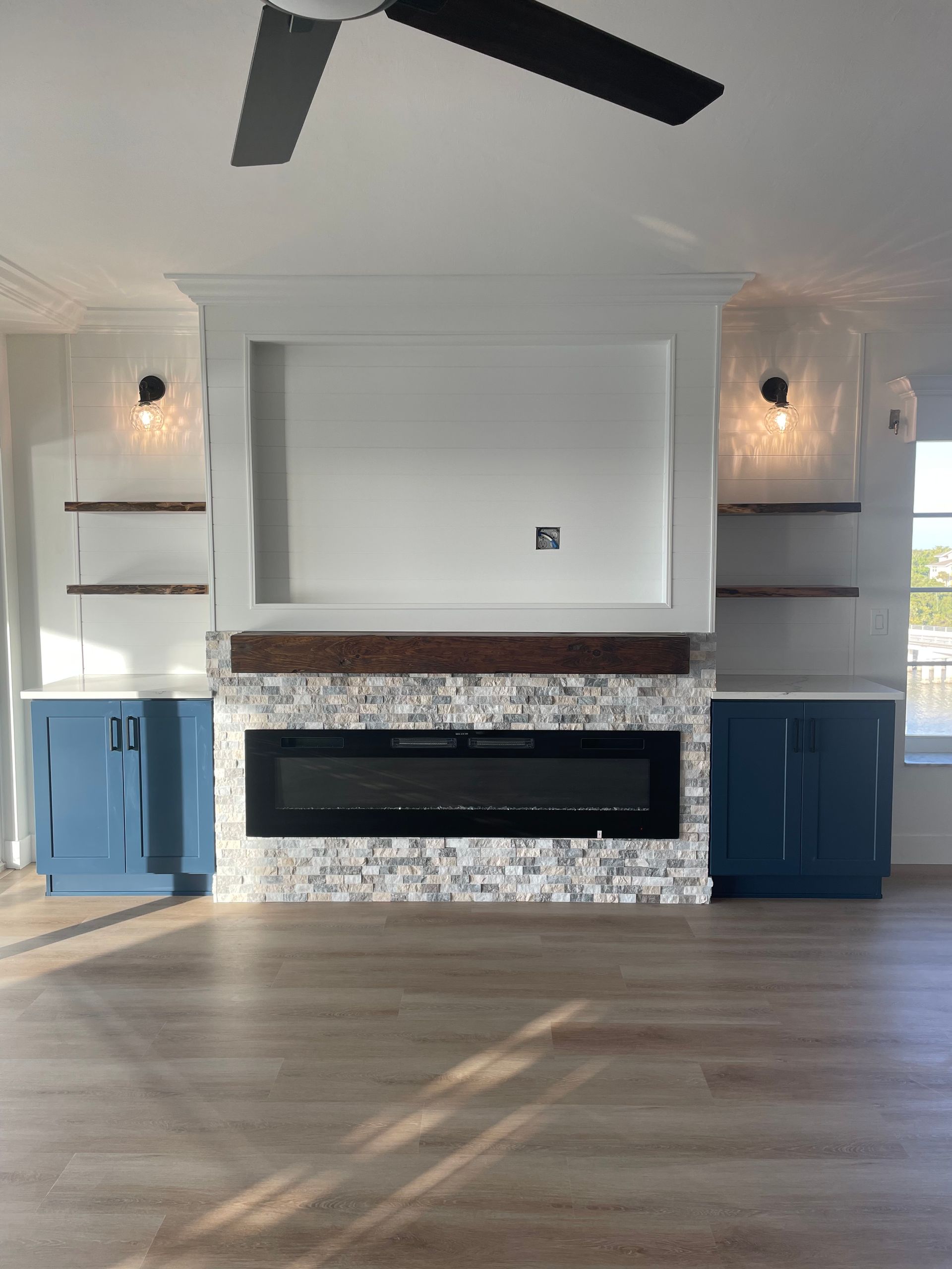 A living room with a fireplace and a ceiling fan
