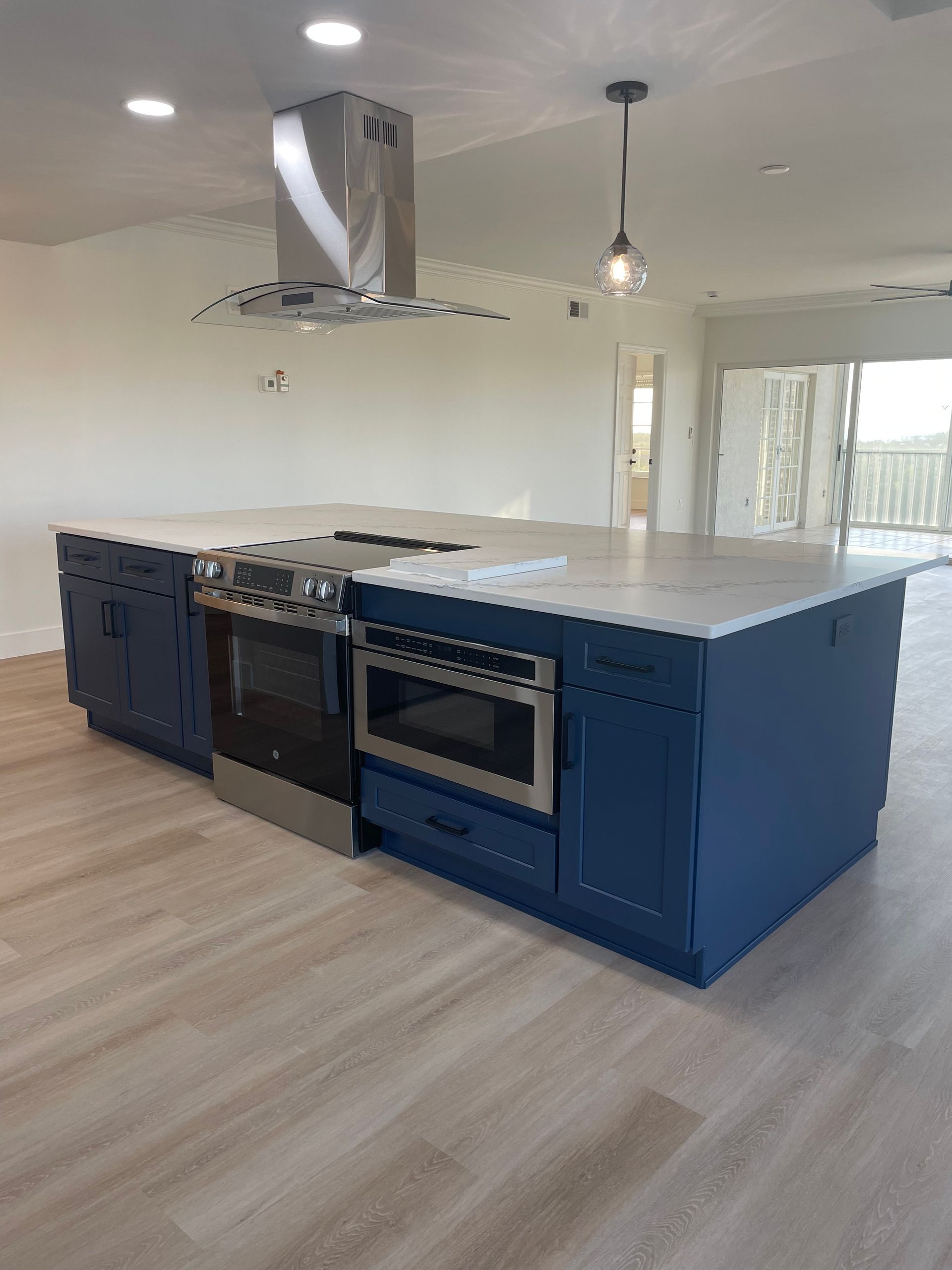 A kitchen with blue cabinets , stainless steel appliances , and a large island.