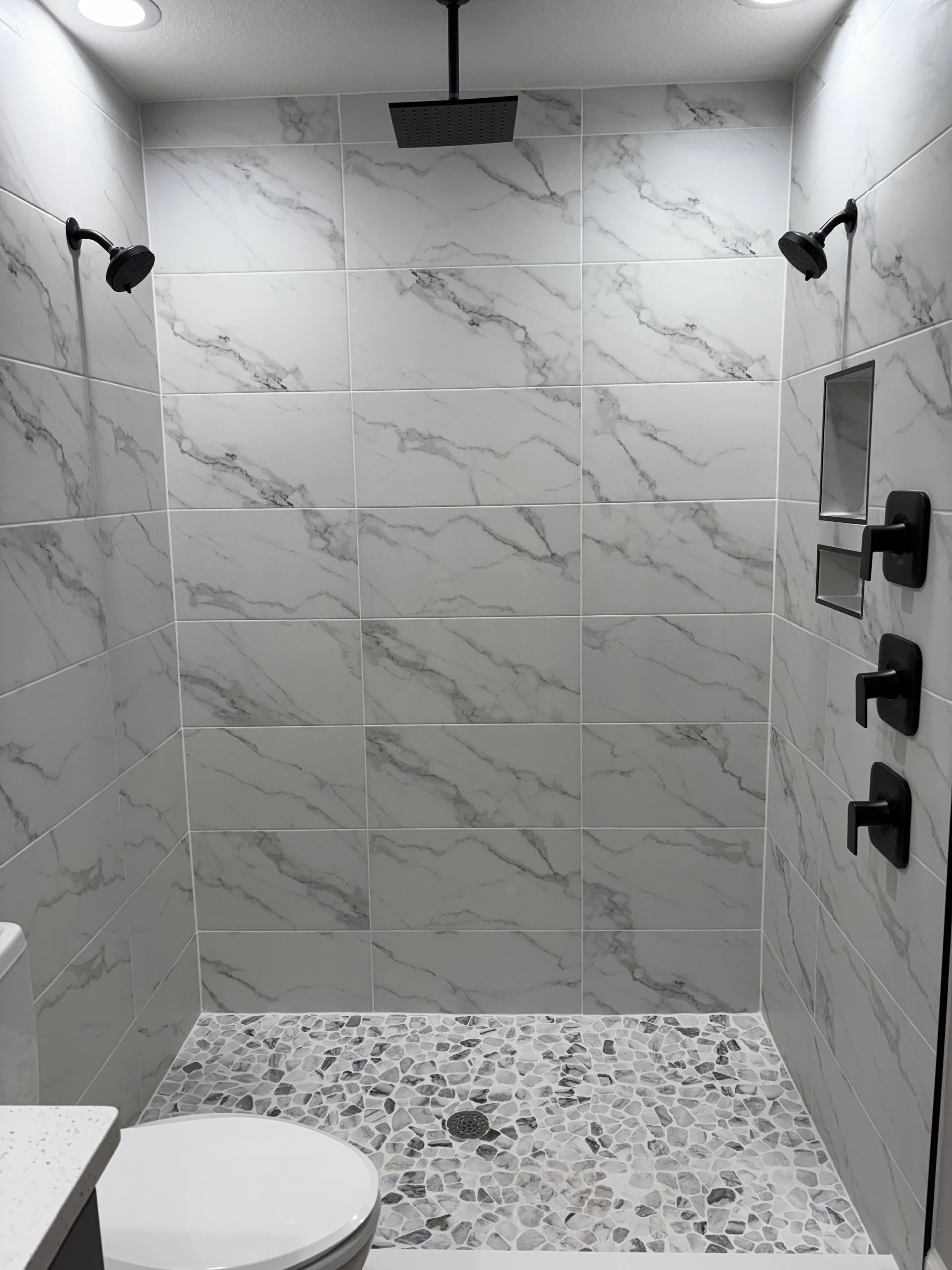 A bathroom with two showers and a toilet.