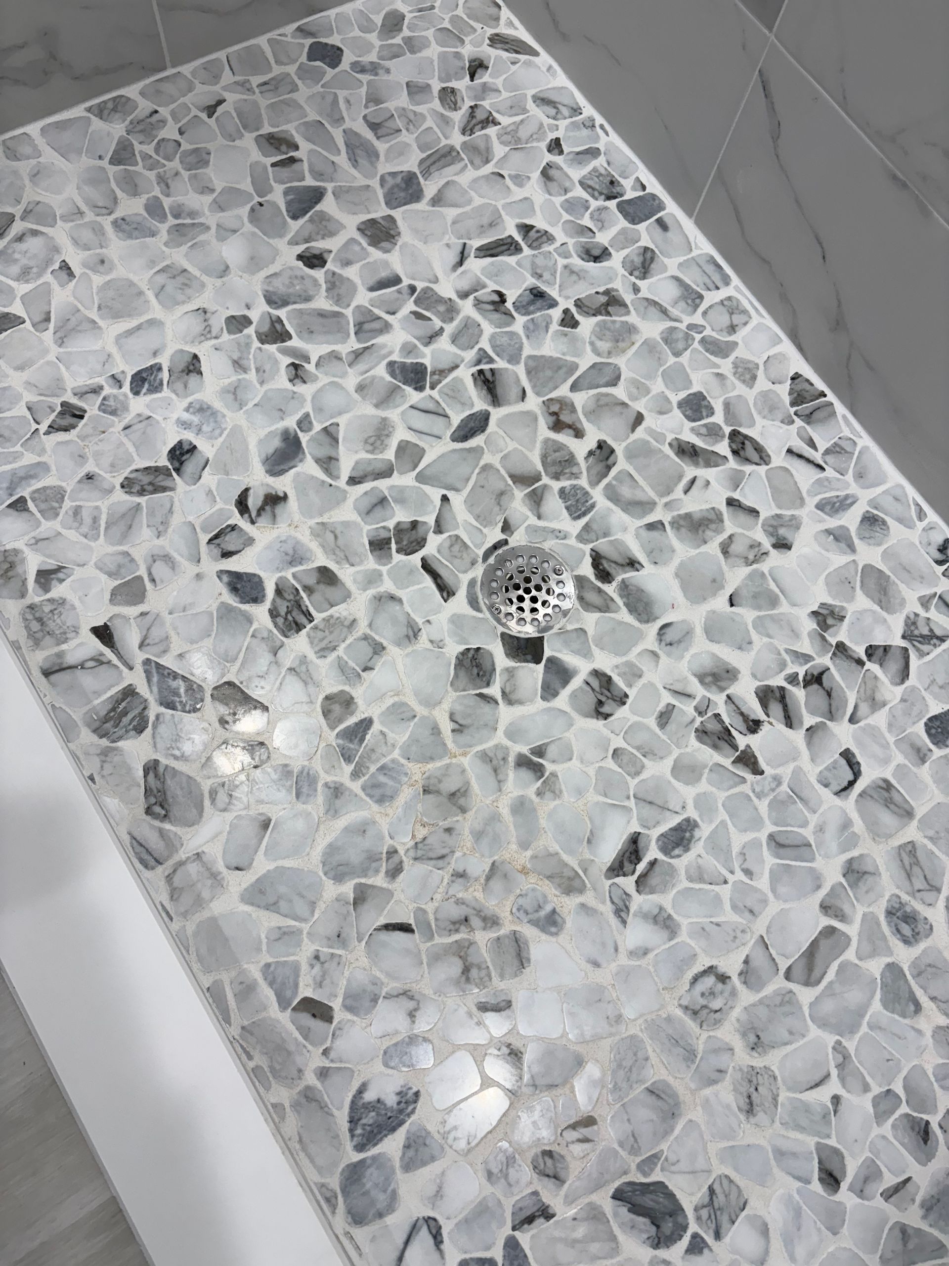 A close up of a shower floor with a drain.