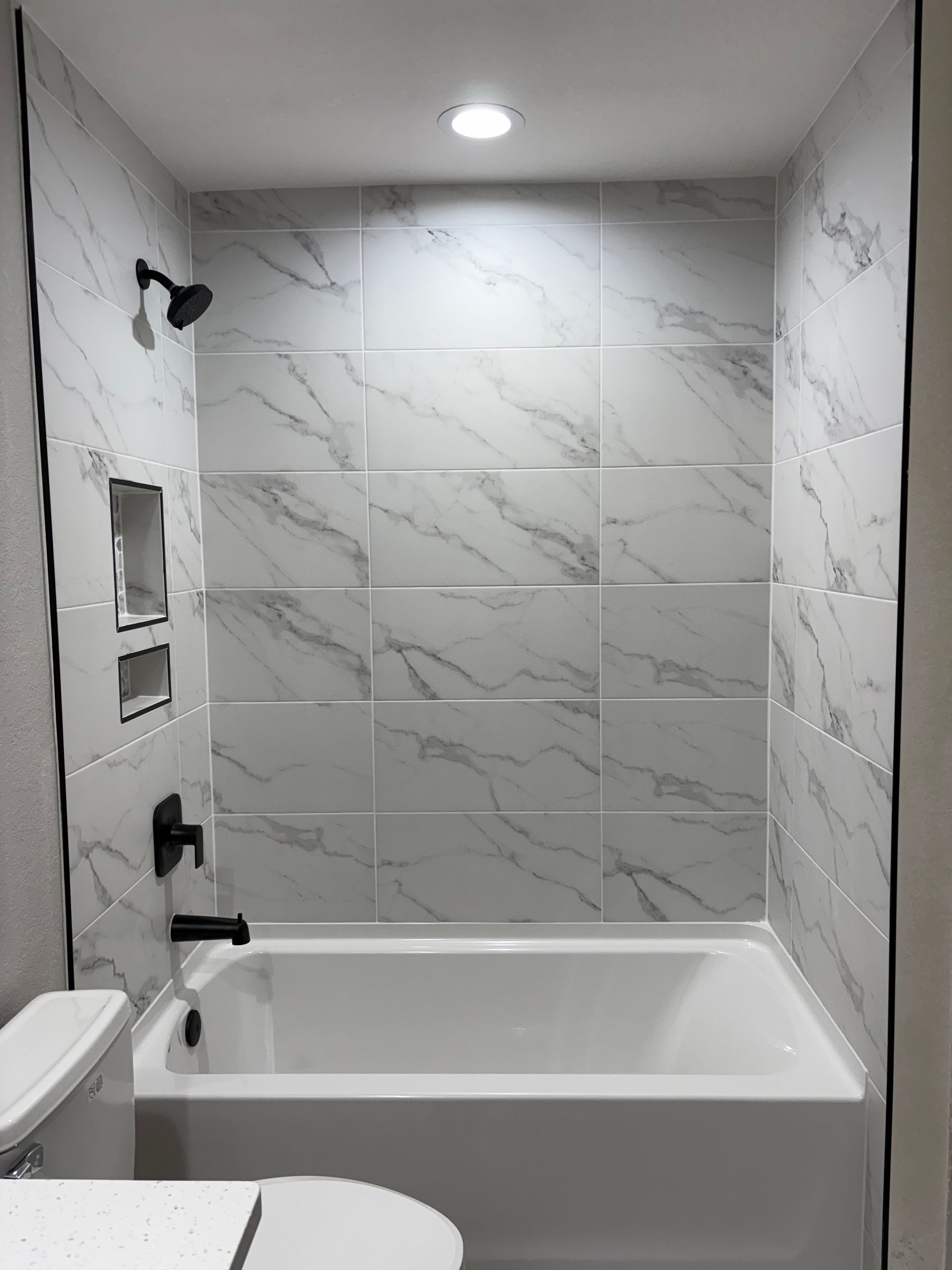 A bathroom with a tub , toilet and shower.