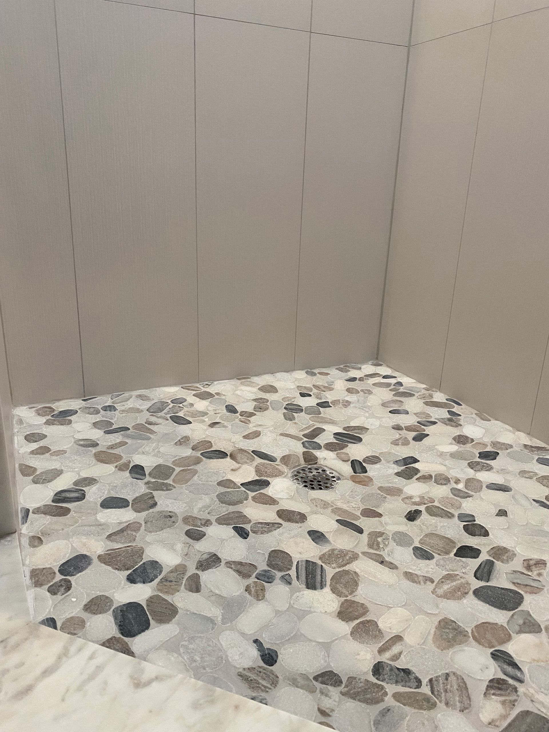 A bathroom with a tiled floor and a drain.