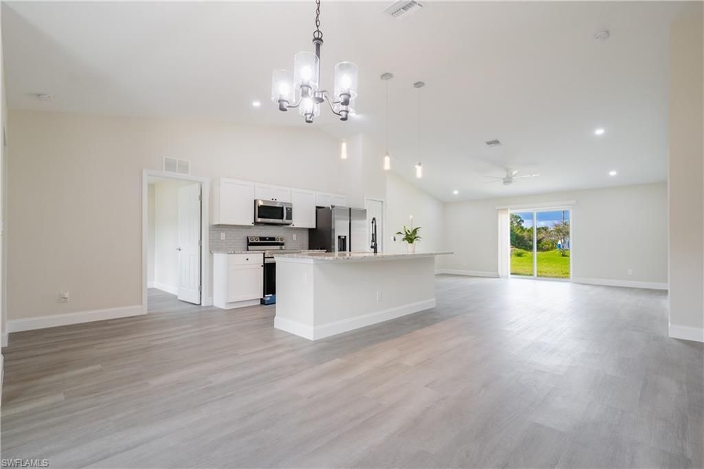 A large empty room with a kitchen and sliding glass doors