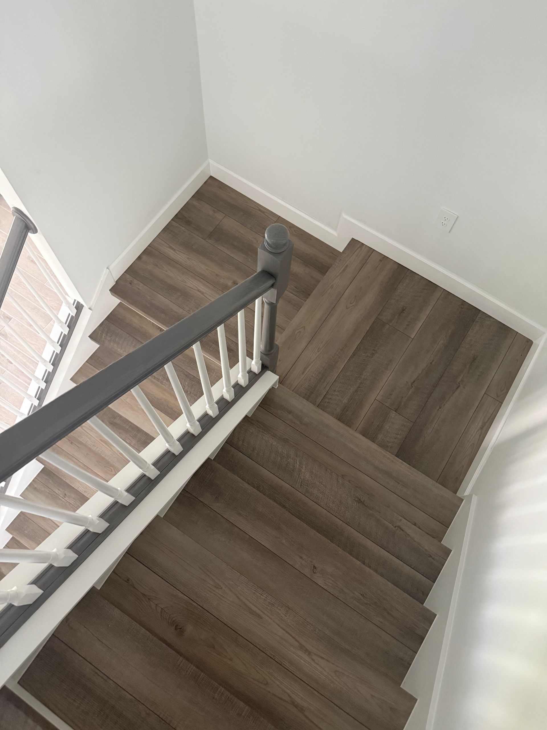 Brown SPC 5.5mm 12mil 20 mil Vinyl Flooring with attached IXPE padding Stone core flooring, brown oak wood look Vinyl click lock flooring with black fan, white modern square baseboard, modern flooring and black fan 