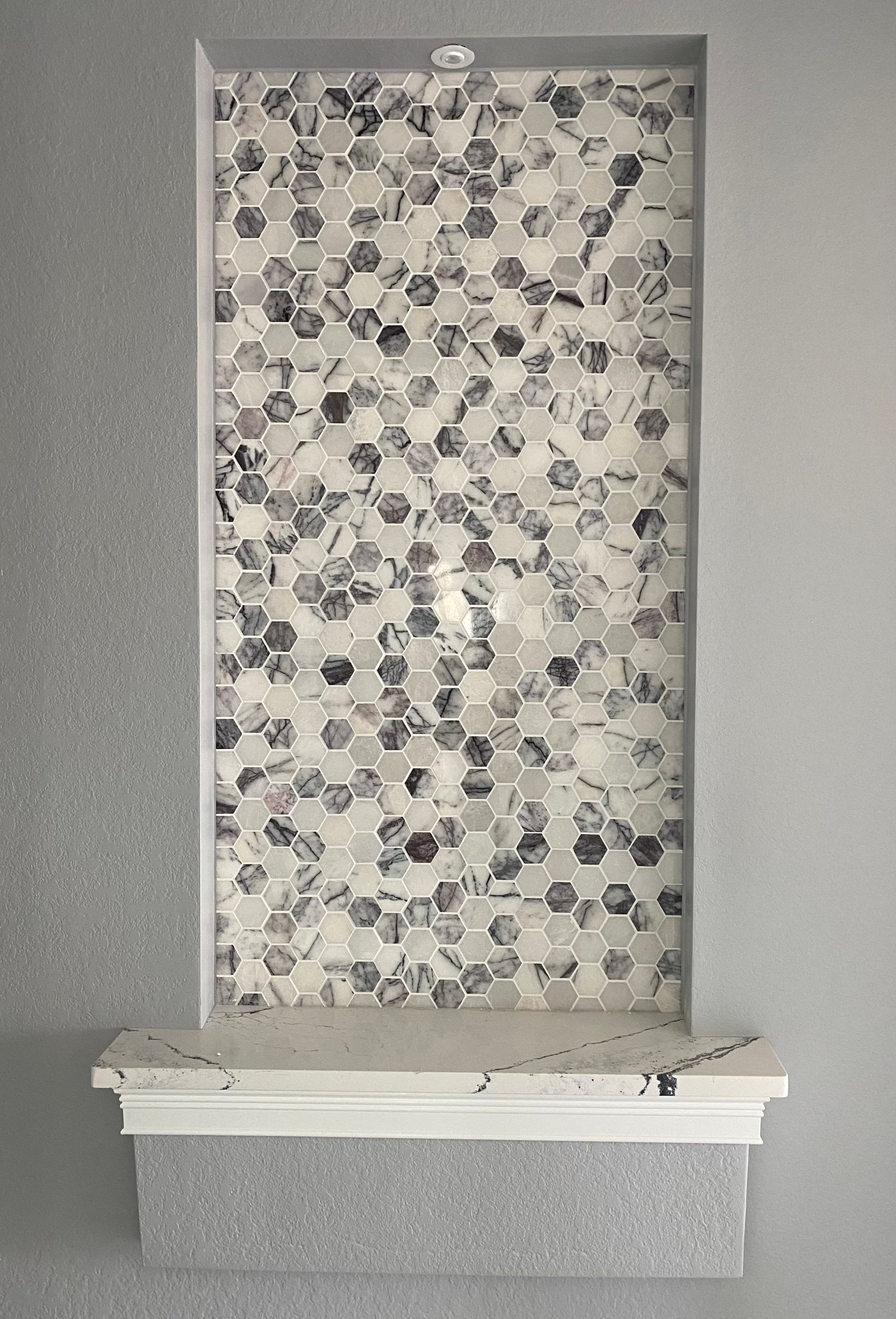 There is a shelf in the wall with a tile wall behind it.