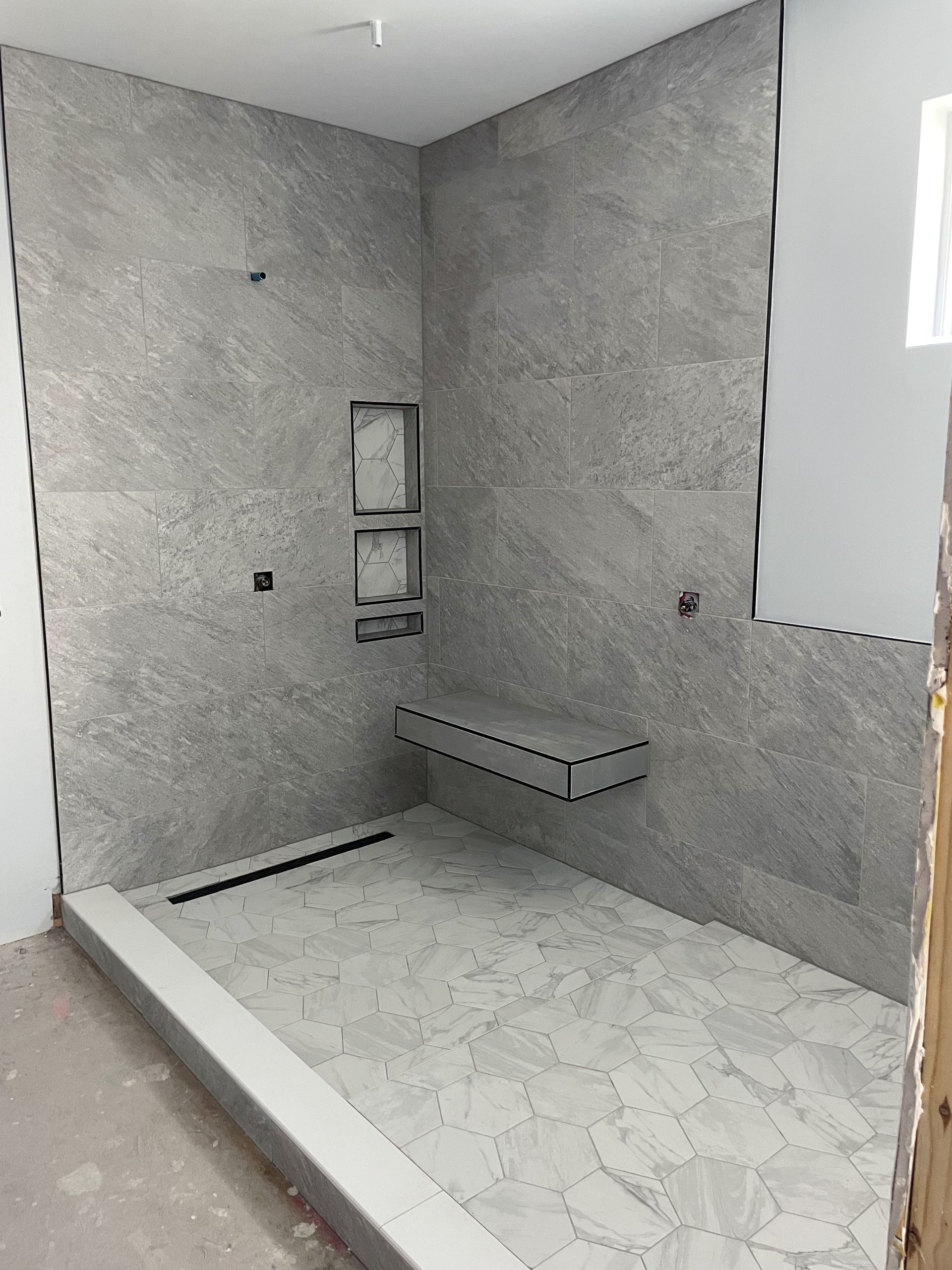 Grey tile bathroom with bench and niche