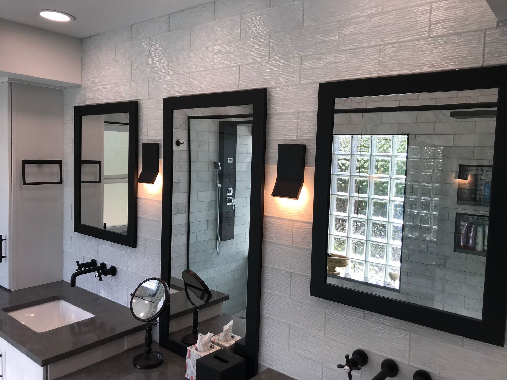 A bathroom with three mirrors and a sink.