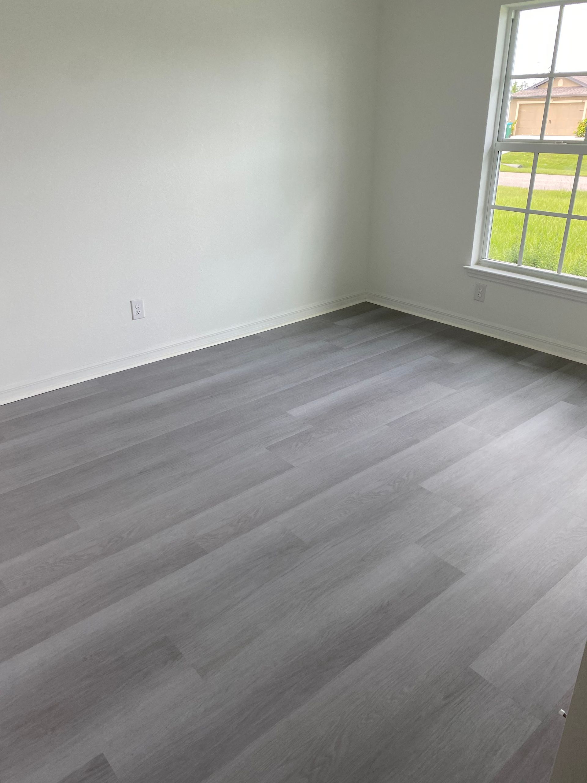 An empty room with a gray floor and a window.