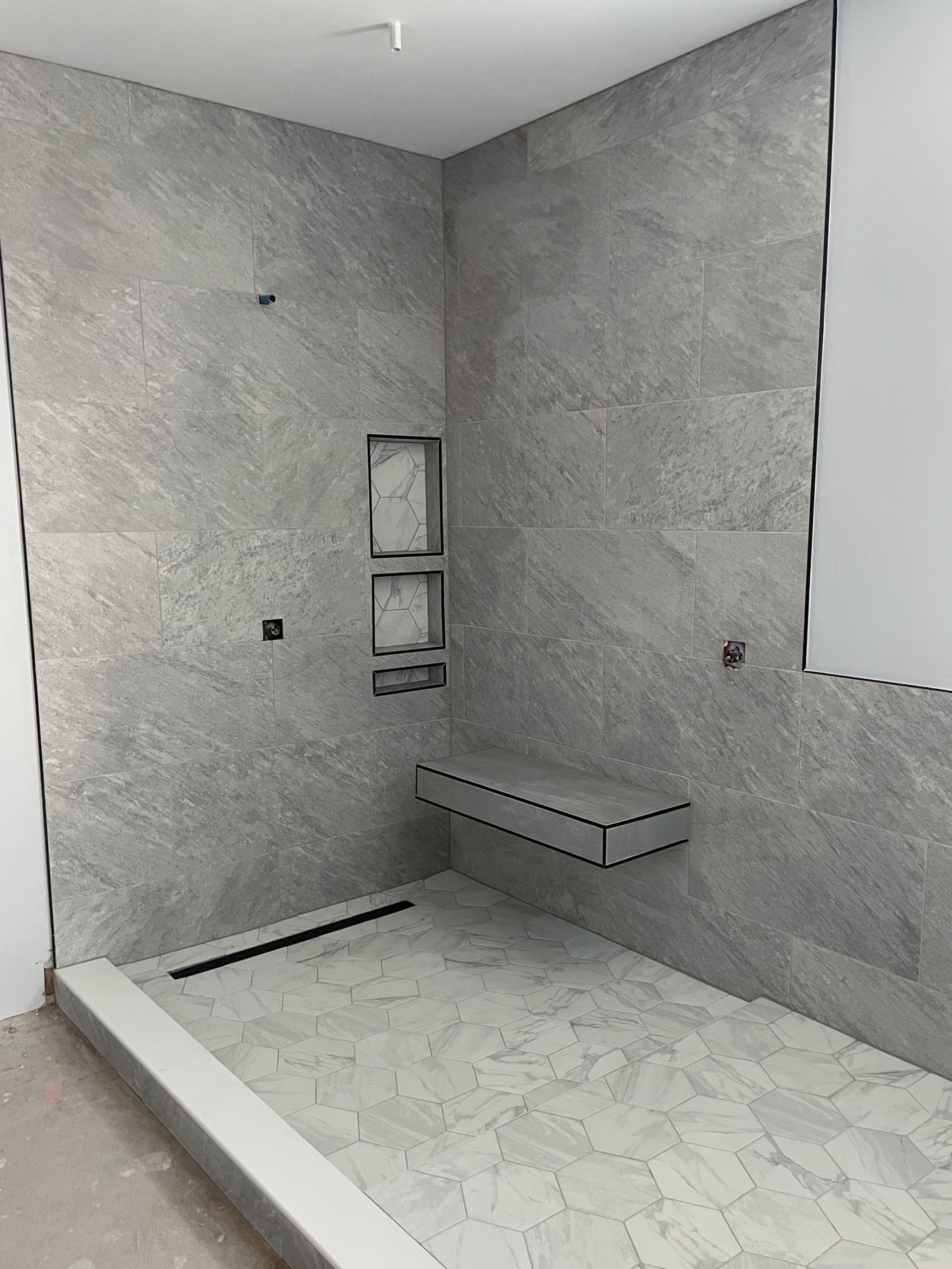Grey tile bathroom with bench and niche