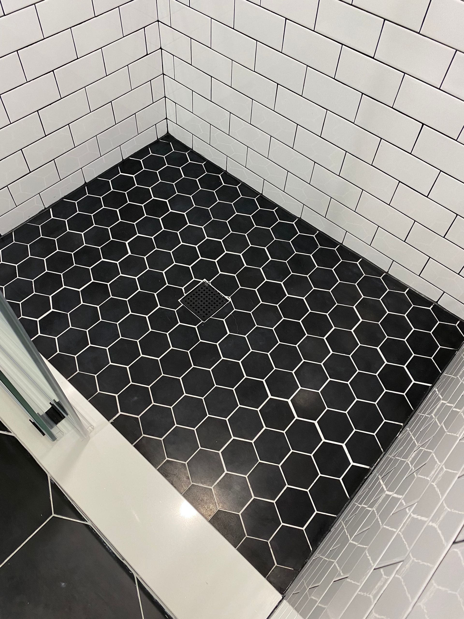 A shower stall with black tiles and white bricks