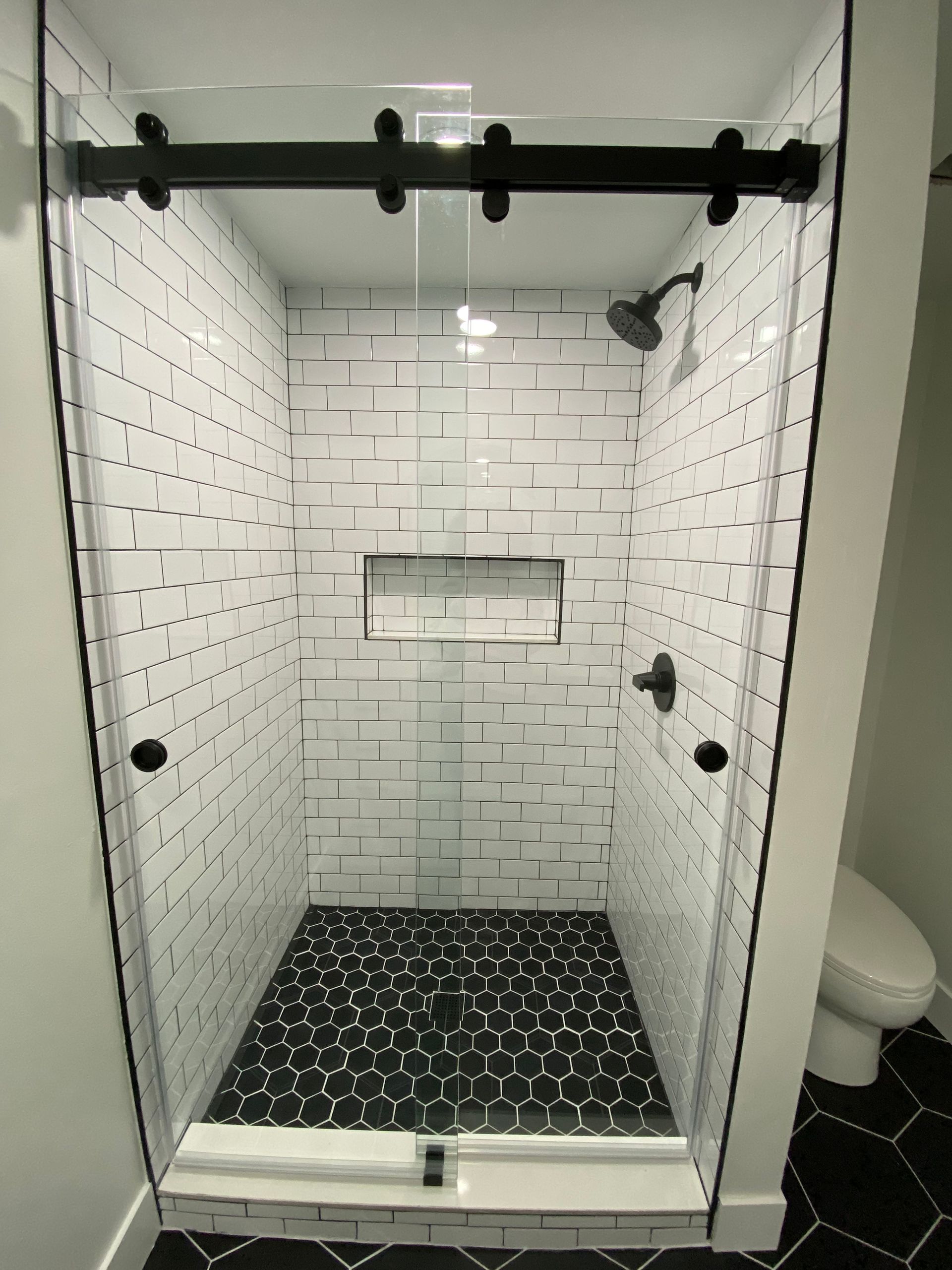 A shower stall with a sliding glass door in a bathroom.