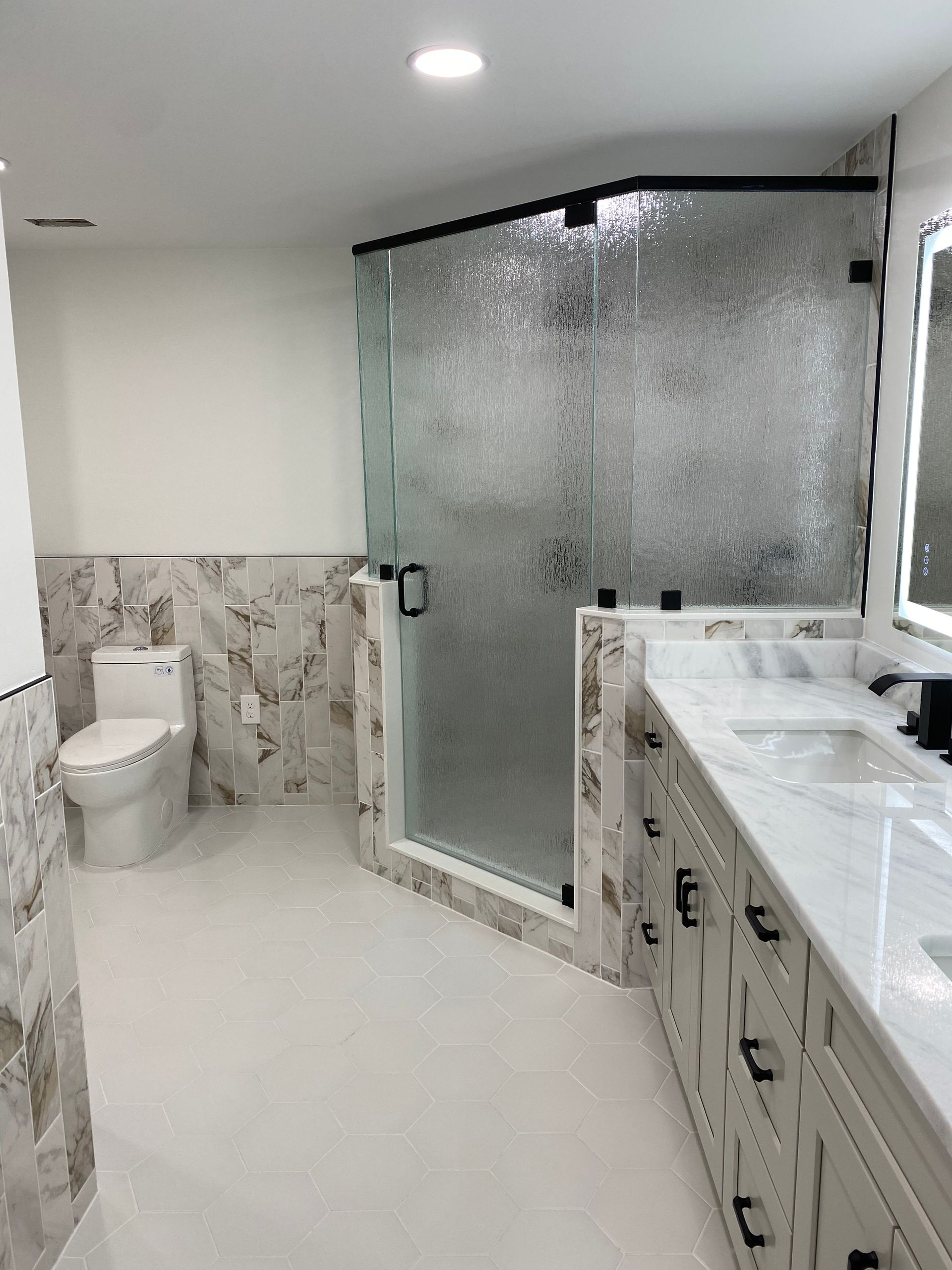 A bathroom with a toilet , sink , shower and mirror.