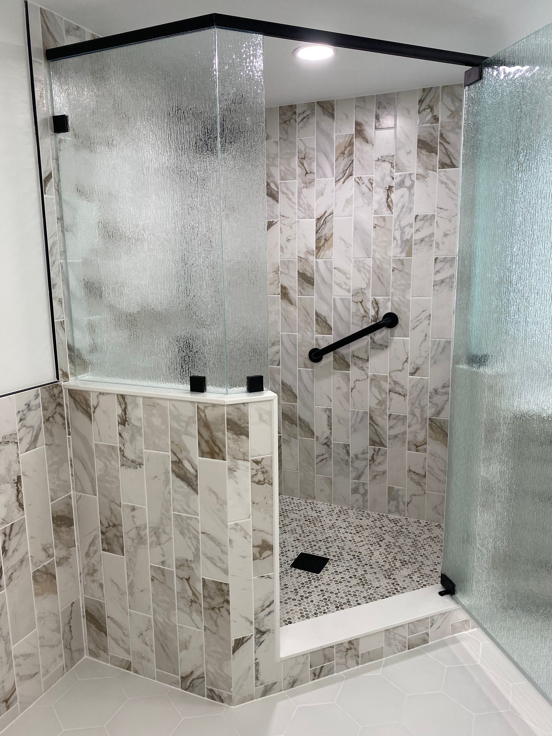 A bathroom with a walk in shower with a glass door.