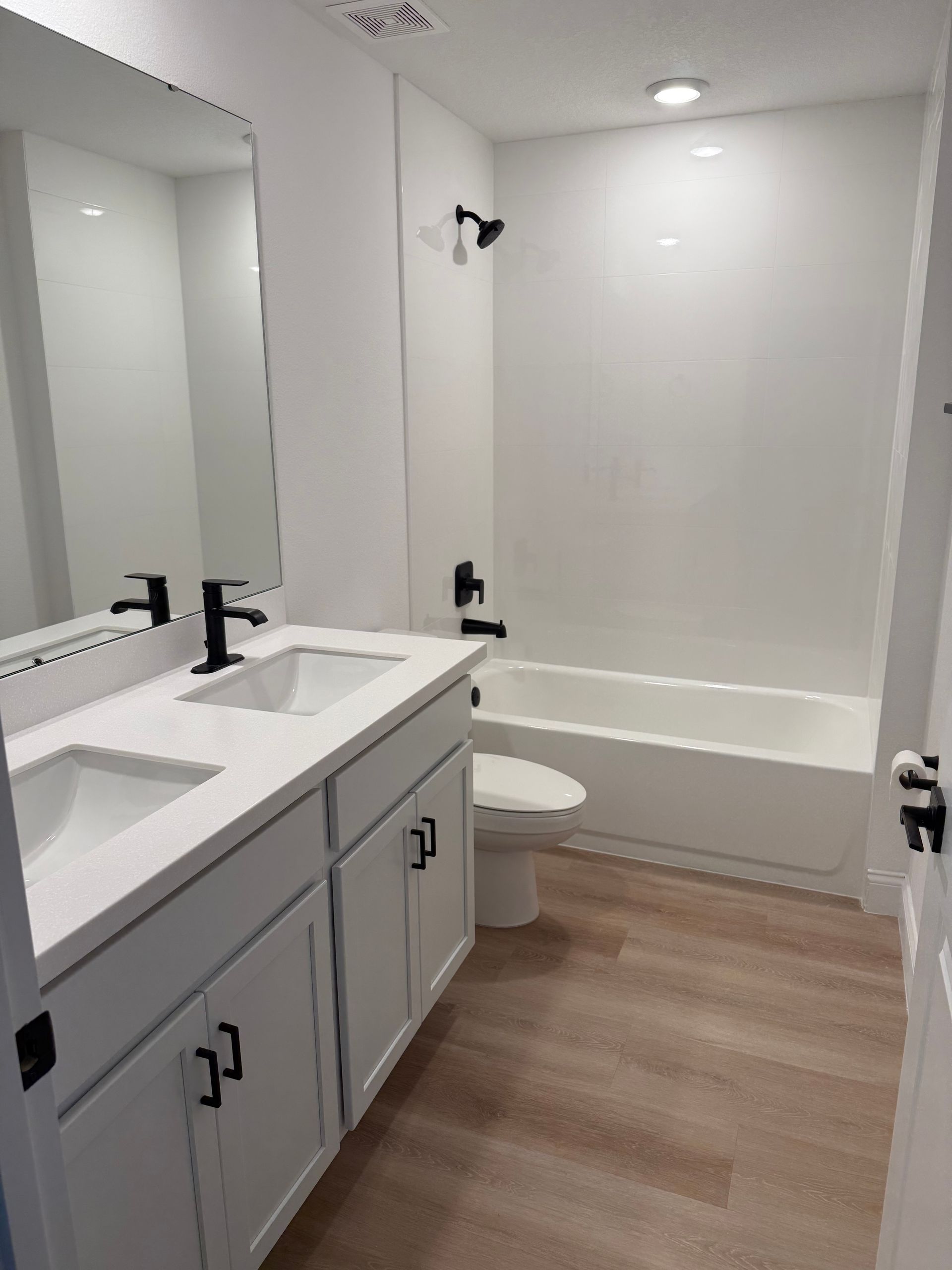 A bathroom with two sinks , a toilet , and a bathtub.
