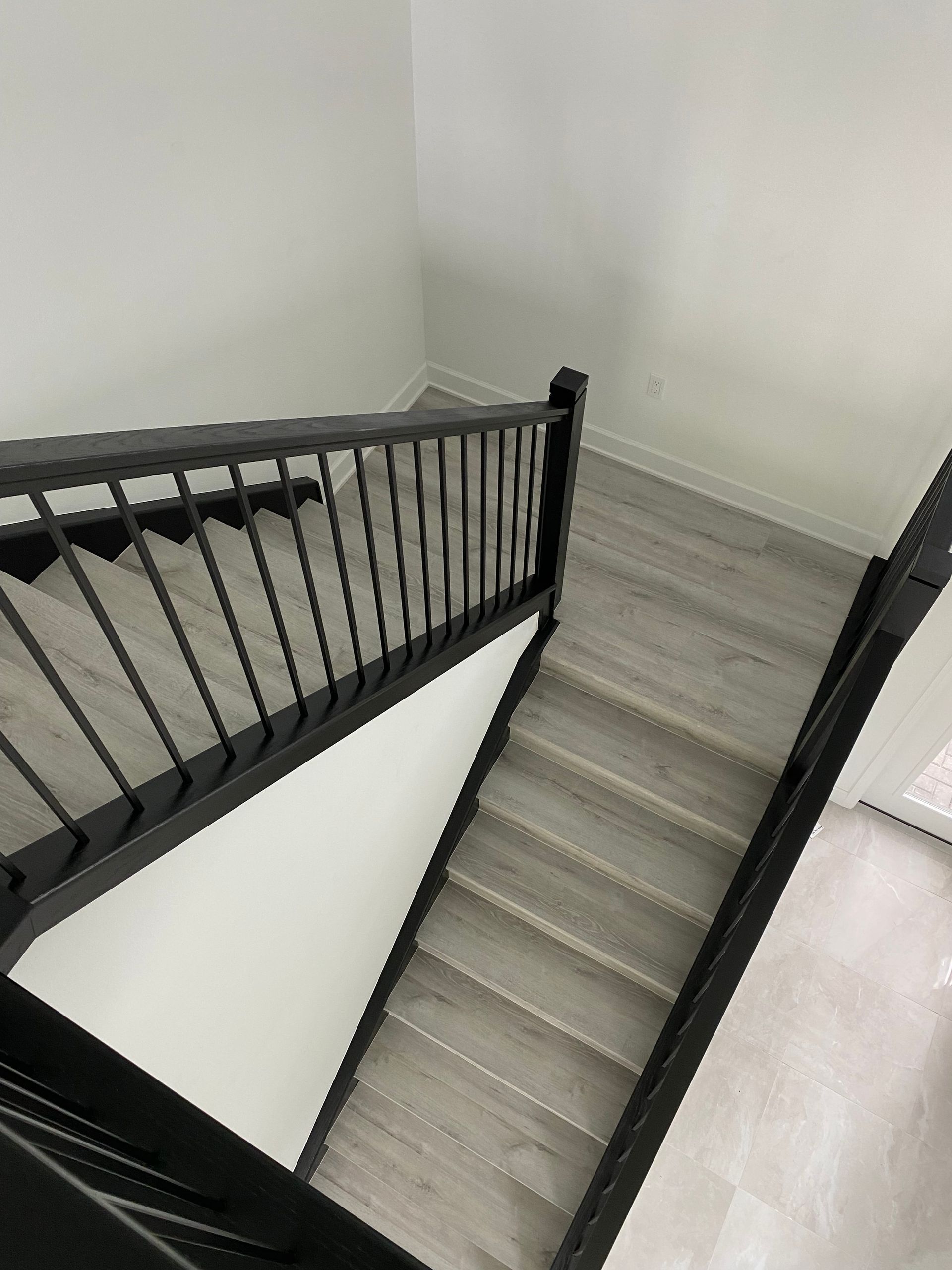 A staircase with a black railing and wooden steps in a room.
