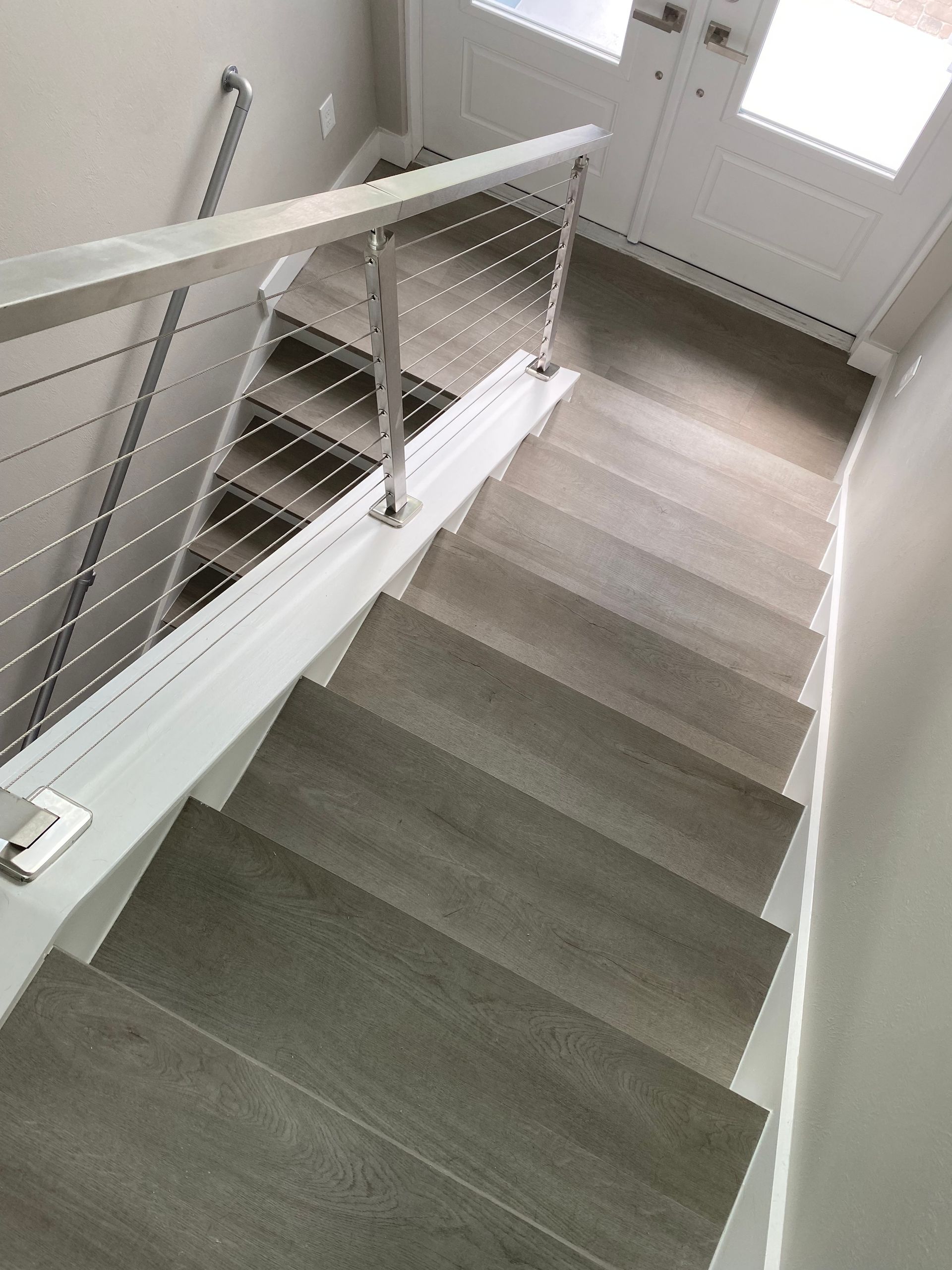 A staircase with a white railing and carpeted steps leading up to a door.