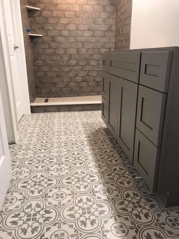 A bathroom with a tiled floor and a brick wall.
