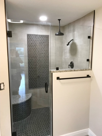 A bathroom with a walk in shower with a glass door.