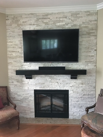 A living room with a fireplace and a flat screen tv on the wall.